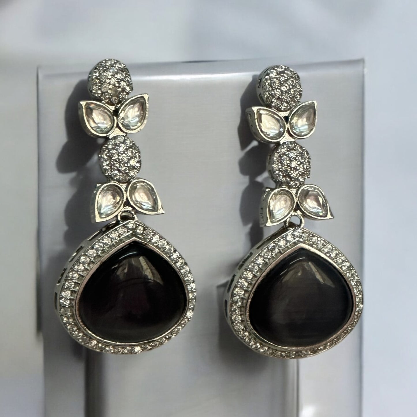 American Diamond Black Partywear Earrings with teardrop black stones and intricate leaf-shaped studded accents.American Diamond Black Partywear Earrings with teardrop black stones and intricate leaf-shaped studded accents.