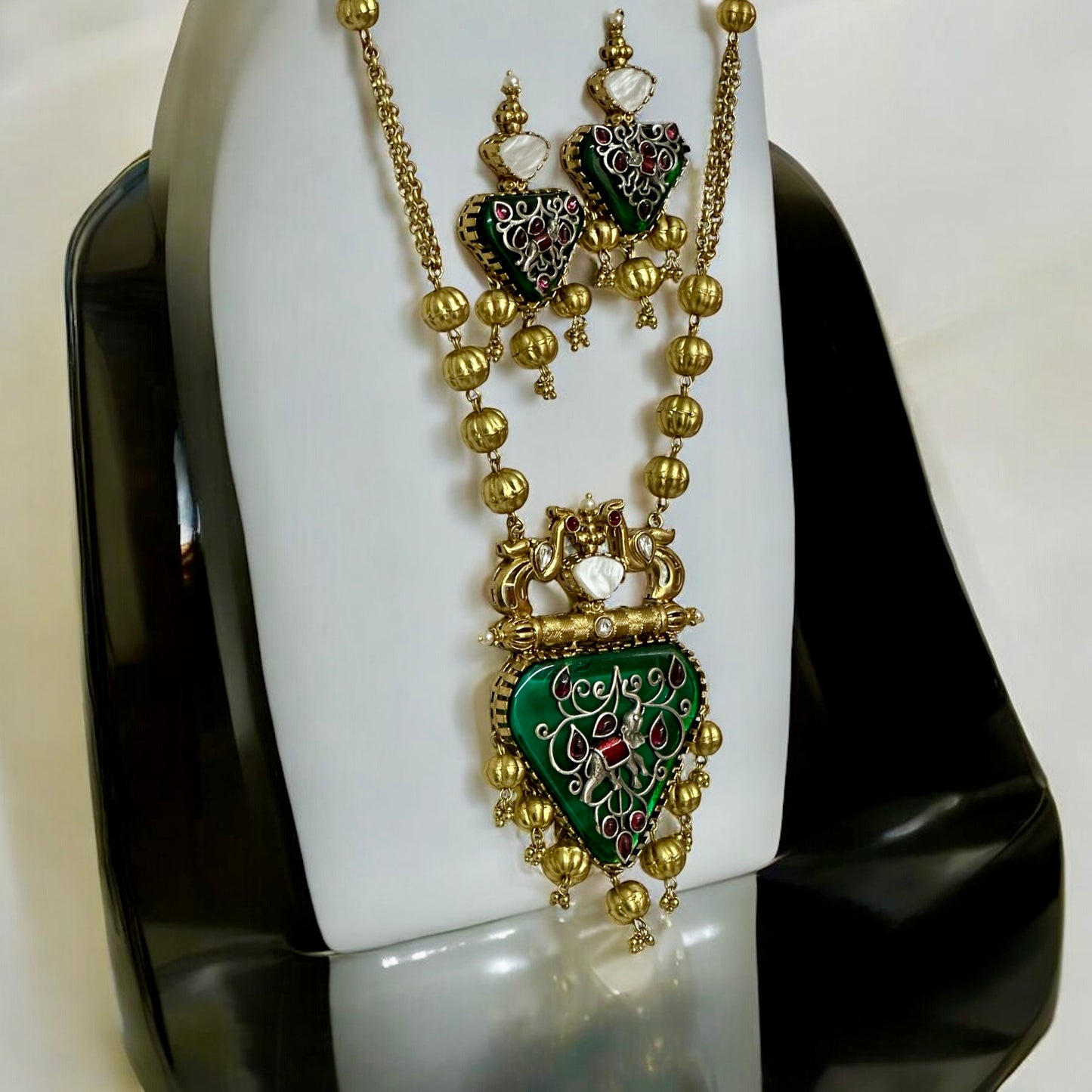 Amrapali-inspired long necklace with green enamel stone pendant and matching earrings on white jewellery display stand β Bella & Diva