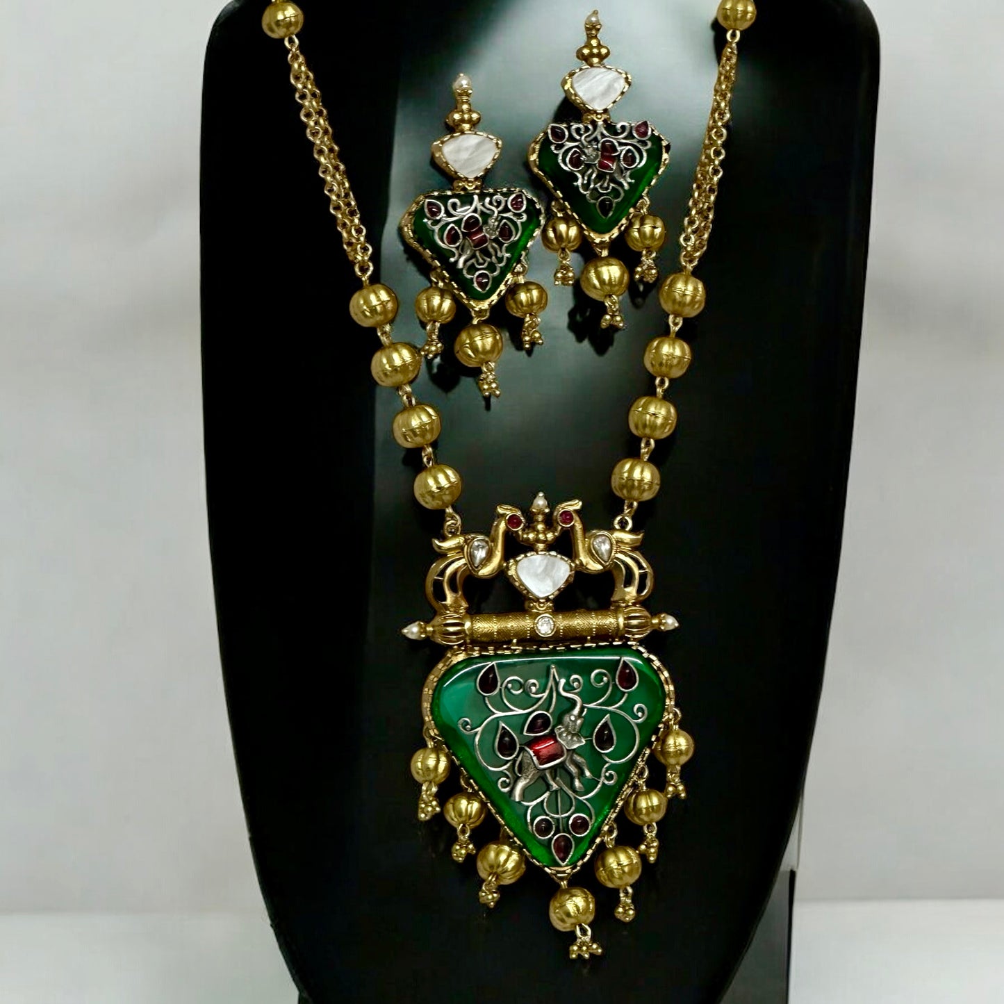 Amrapali-inspired long necklace with green enamel stone pendant and matching earrings on black jewellery display stand β Bella & Diva