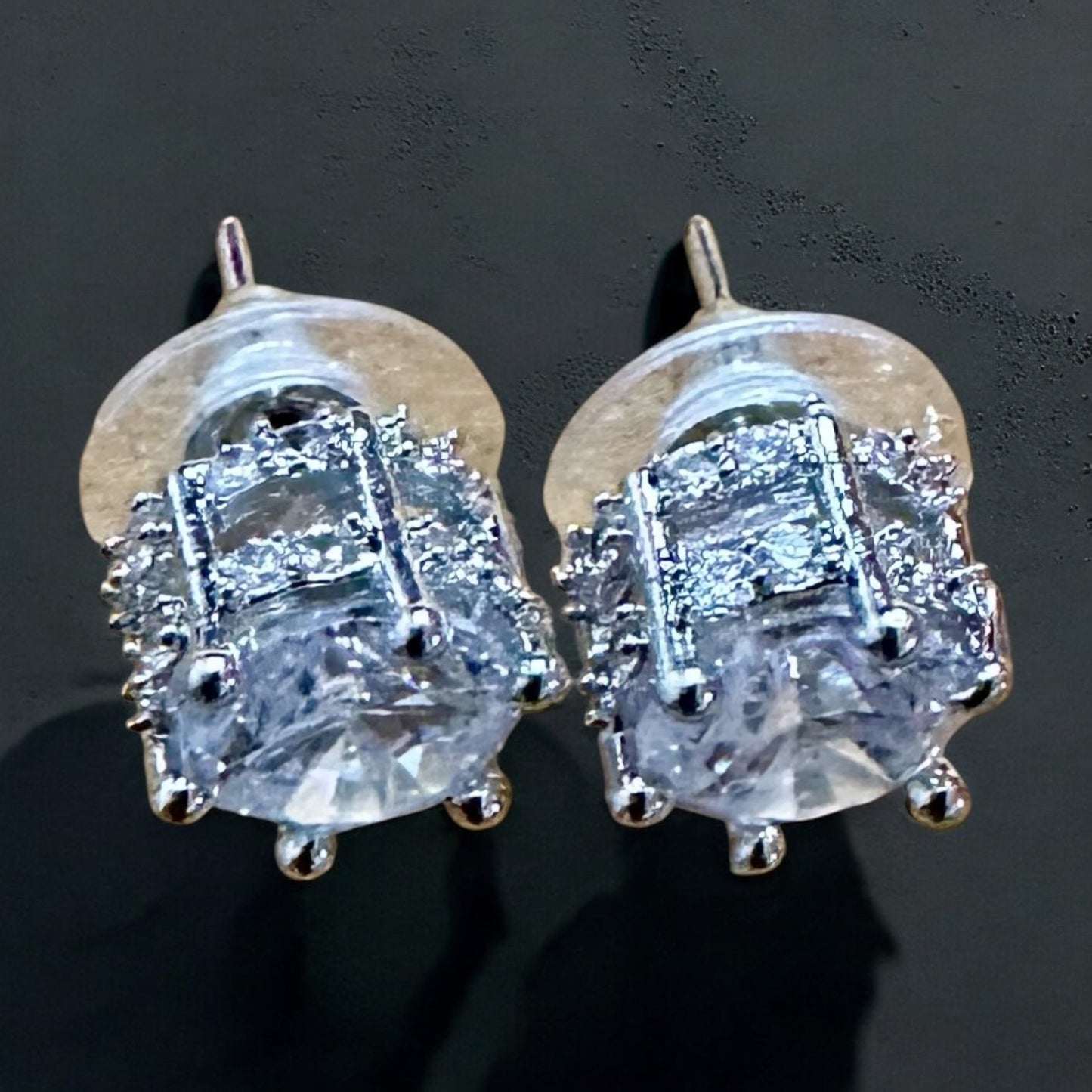 Silver American Diamond studs lying on a dull black background