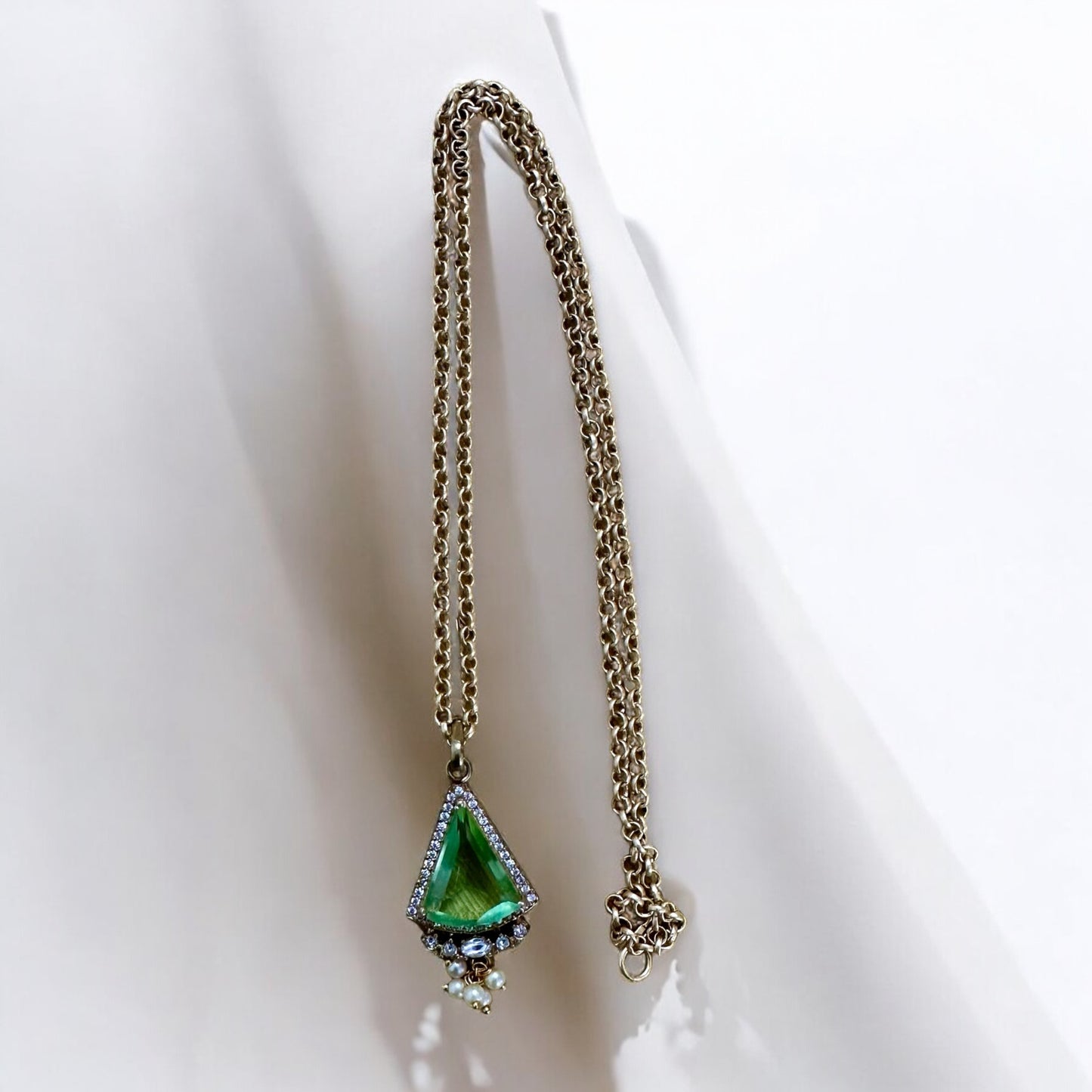 Green stoned Doublet American Diamond Pendant In Apala Polish hanging on a white coloured background.