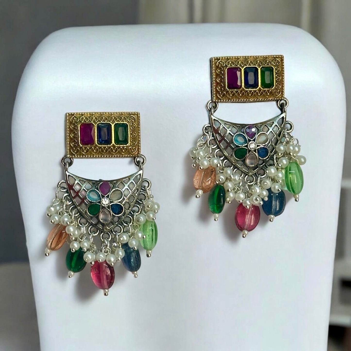 Dual tone silver look alike earrings with multicolour beads placed on a white coloured jewellery display stand.