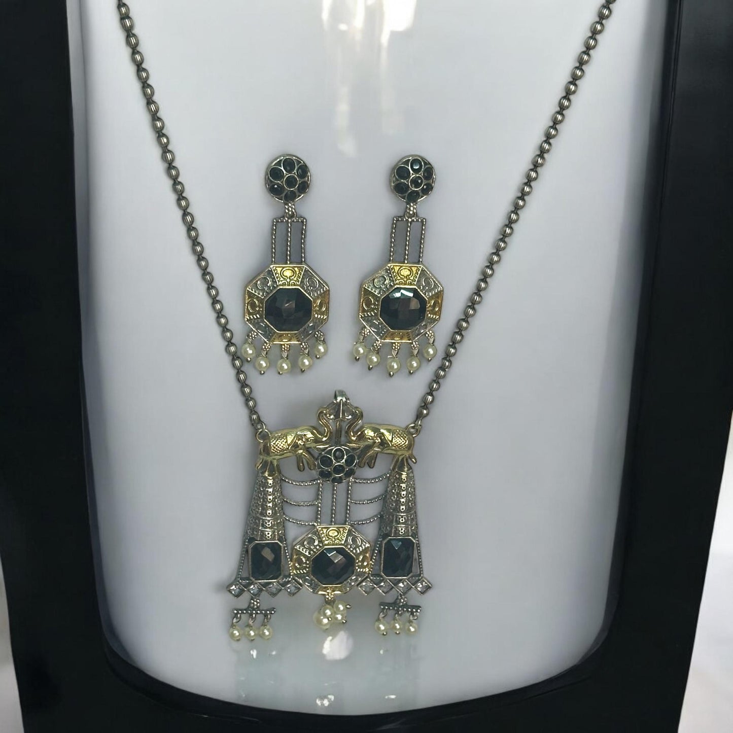 Dual Tone Silver Replica Necklace Set in green and golden color featuring a detailed pendant with green stones and hanging pearls, displayed on a white mannequin with a soft black and white gradient background.
