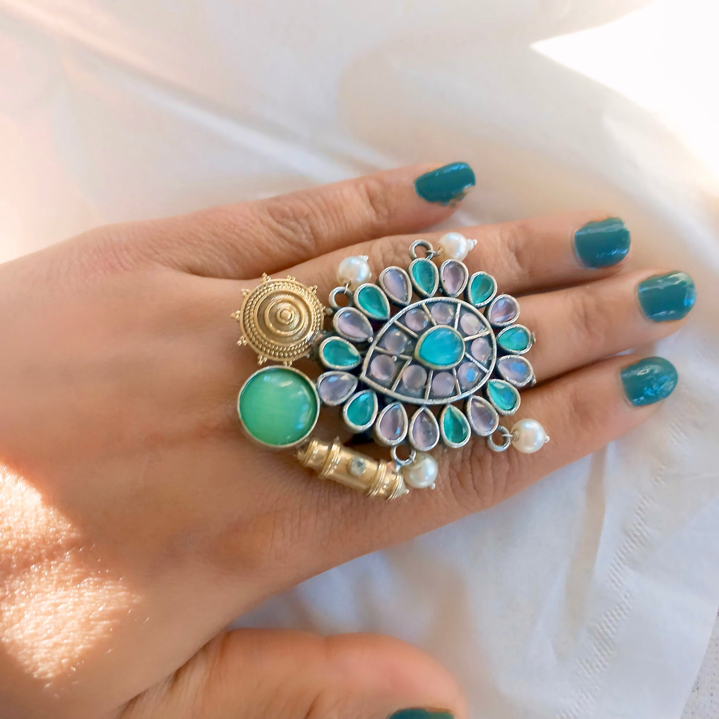 Fusion ring with multicolor gemstones on a hand model.