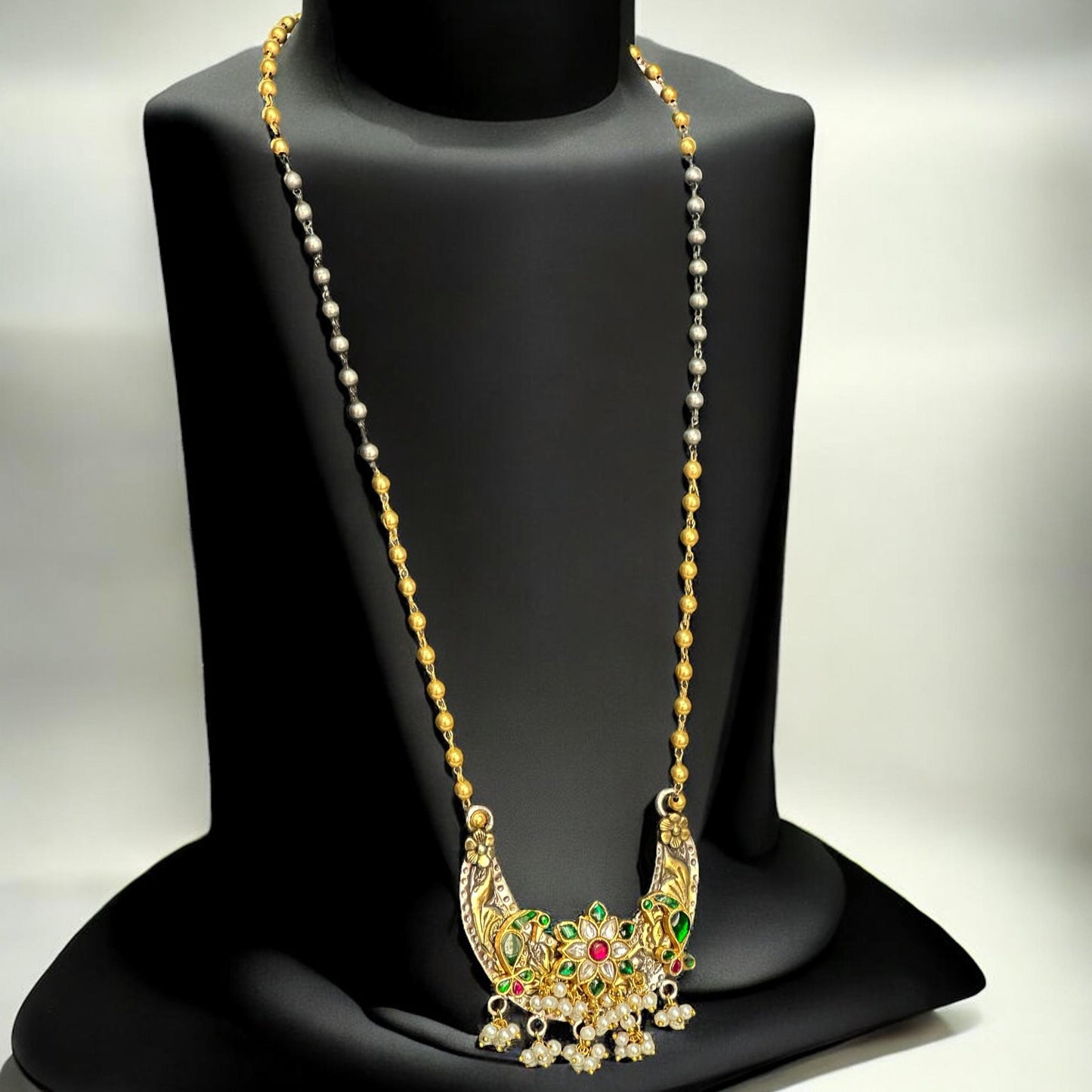 Jadau Pachi Kundan pendant in a fusion design with floral detailing, suspended from a long Amrapali dual-tone chain, displayed on a black mannequin.