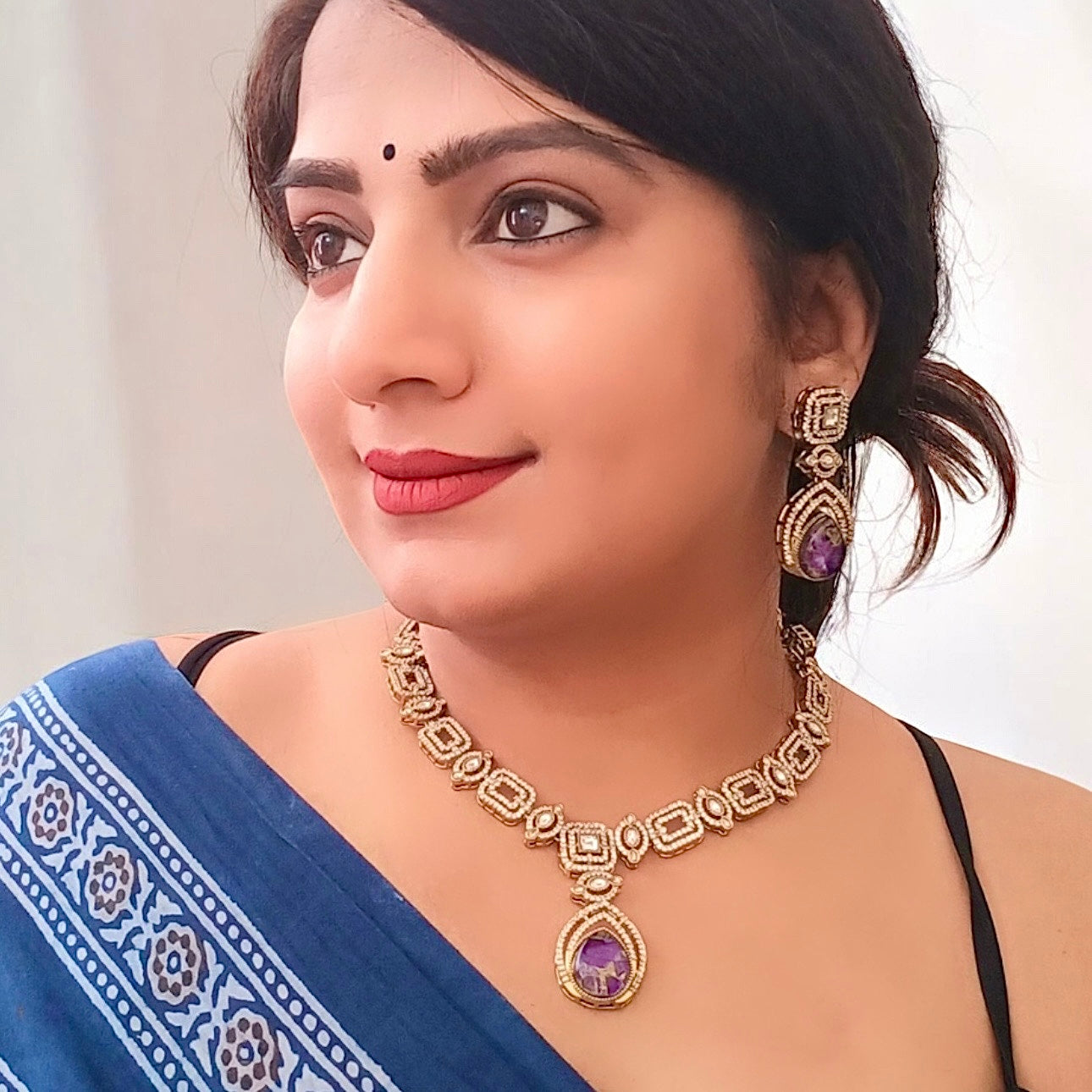 A model displaying Moissanite Kundan With Doublet Amethyst purple Stone necklace set with earrings.
