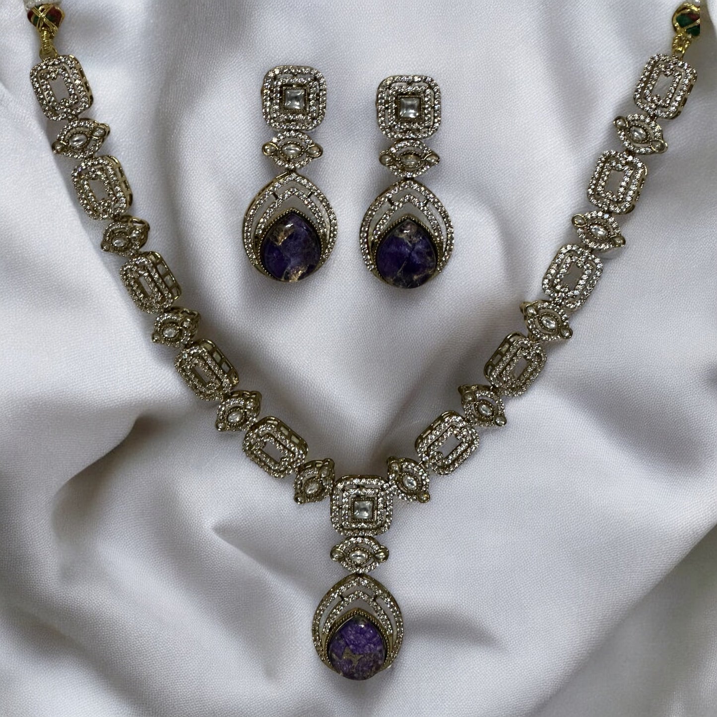 Moissanite Kundan With Doublet Amethyst purple Stone necklace set with earrings lying on a white colored fabric background.