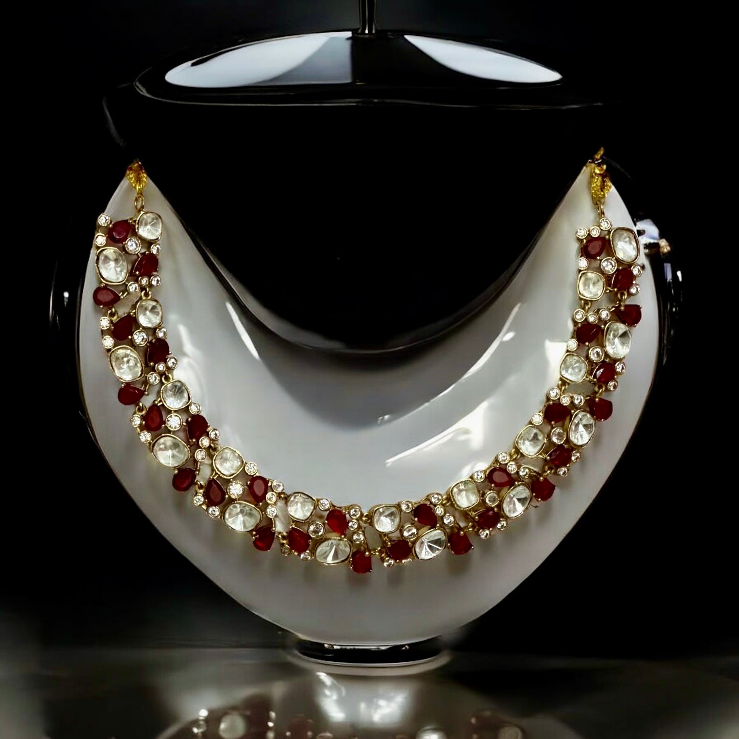 Premium Polki Kundan necklace with red diamond accents and matching earrings on white black jewellery display stand background β Bella & Diva