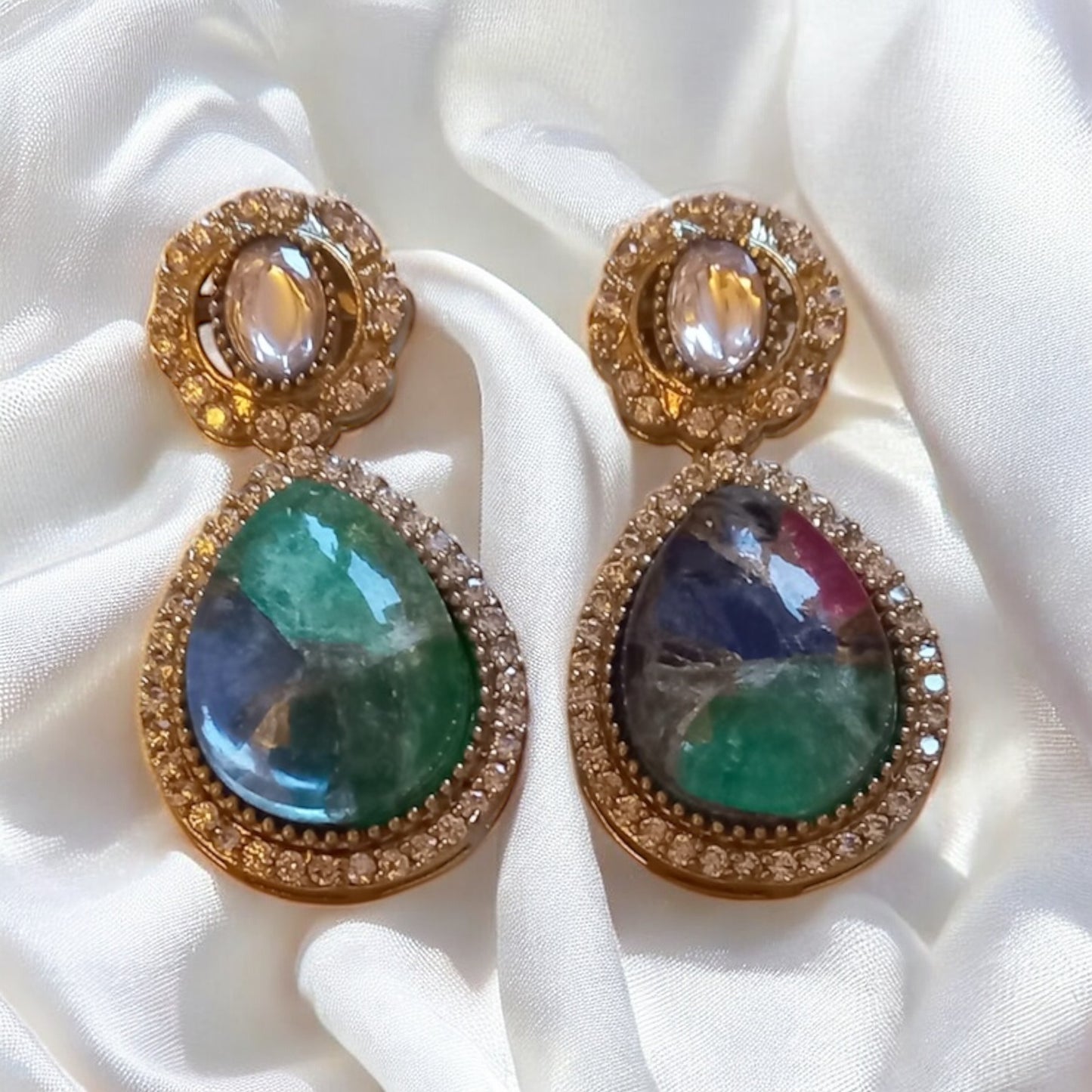 Premium moissanite green and ruby multi-colour doublet stones earrings, placed on white satin fabric