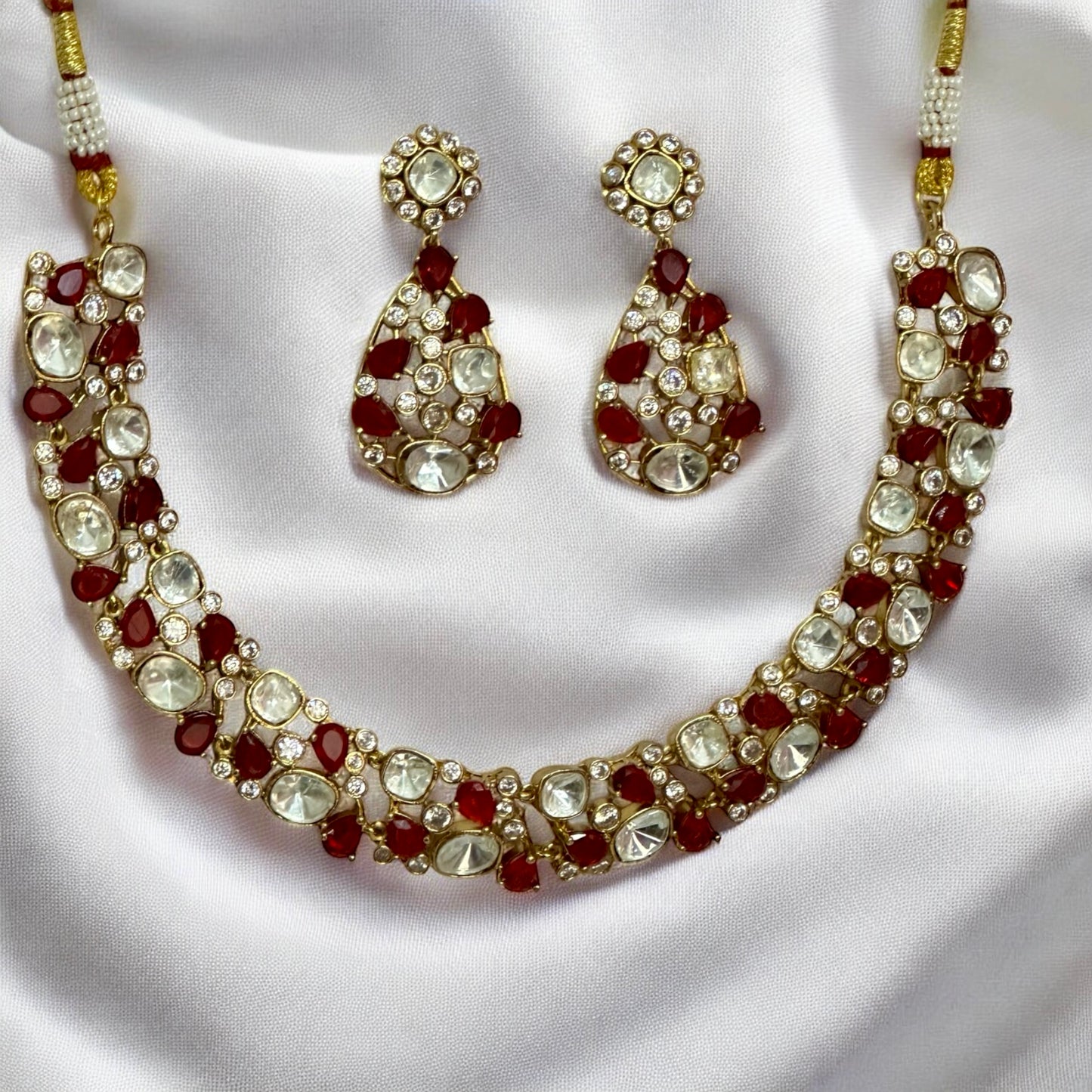 Premium Polki Kundan necklace set with red diamond accents and matching earrings on white silk background β Bella & Diva