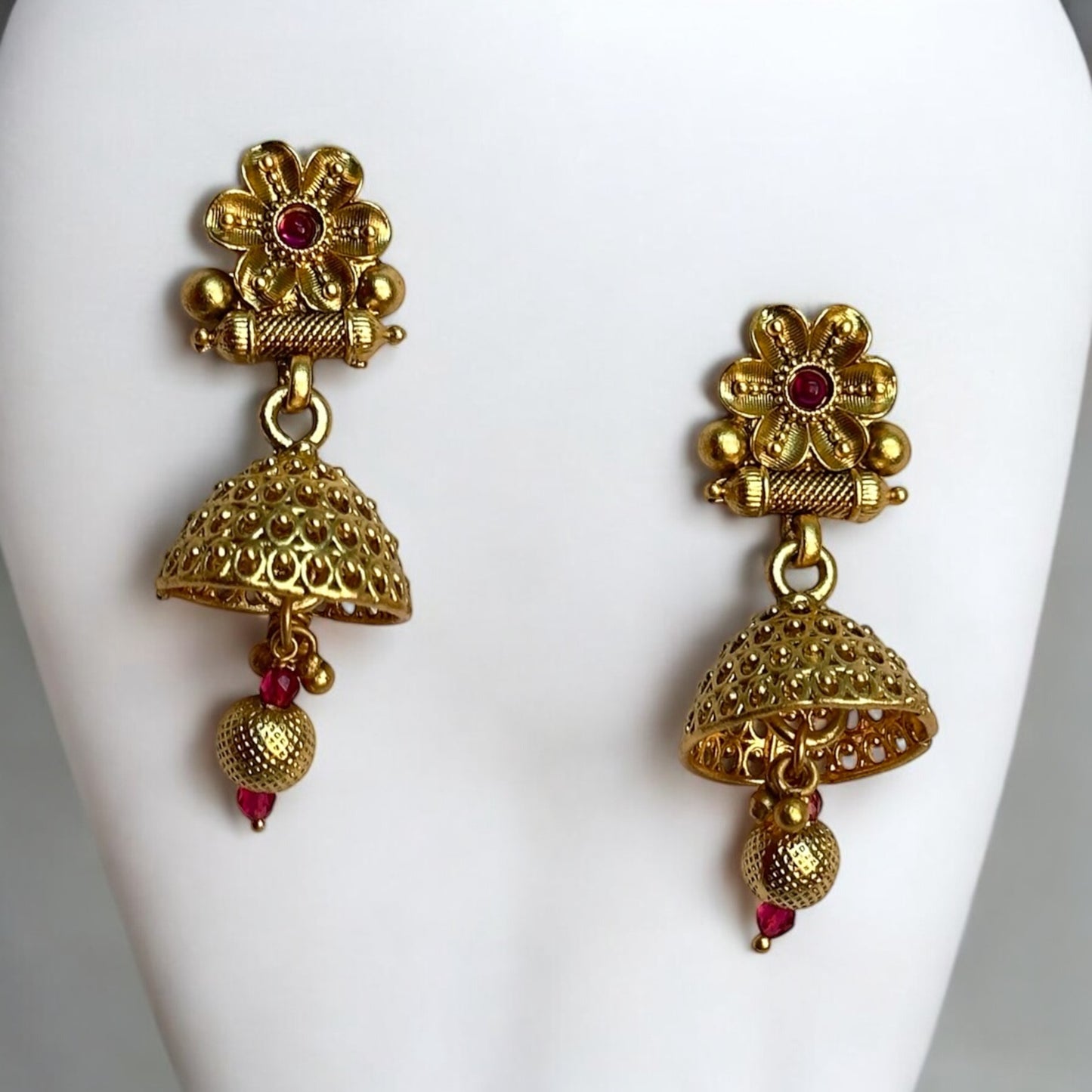 A Premium gold-plated kundan rajwadi jhumki style earrings are placed on a white coloured jewellery display stand.