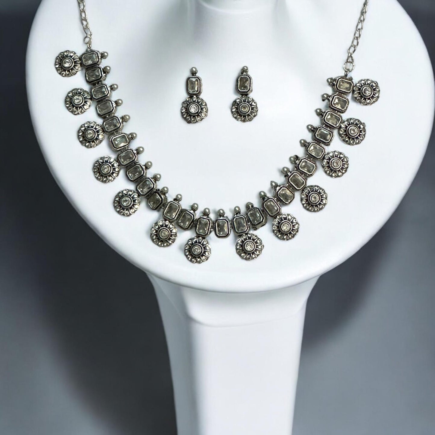 Silver look alike necklace set with white American diamond stones, oxidised silver floral design, displayed on white mannequin – ethnic jewellery for women UK.