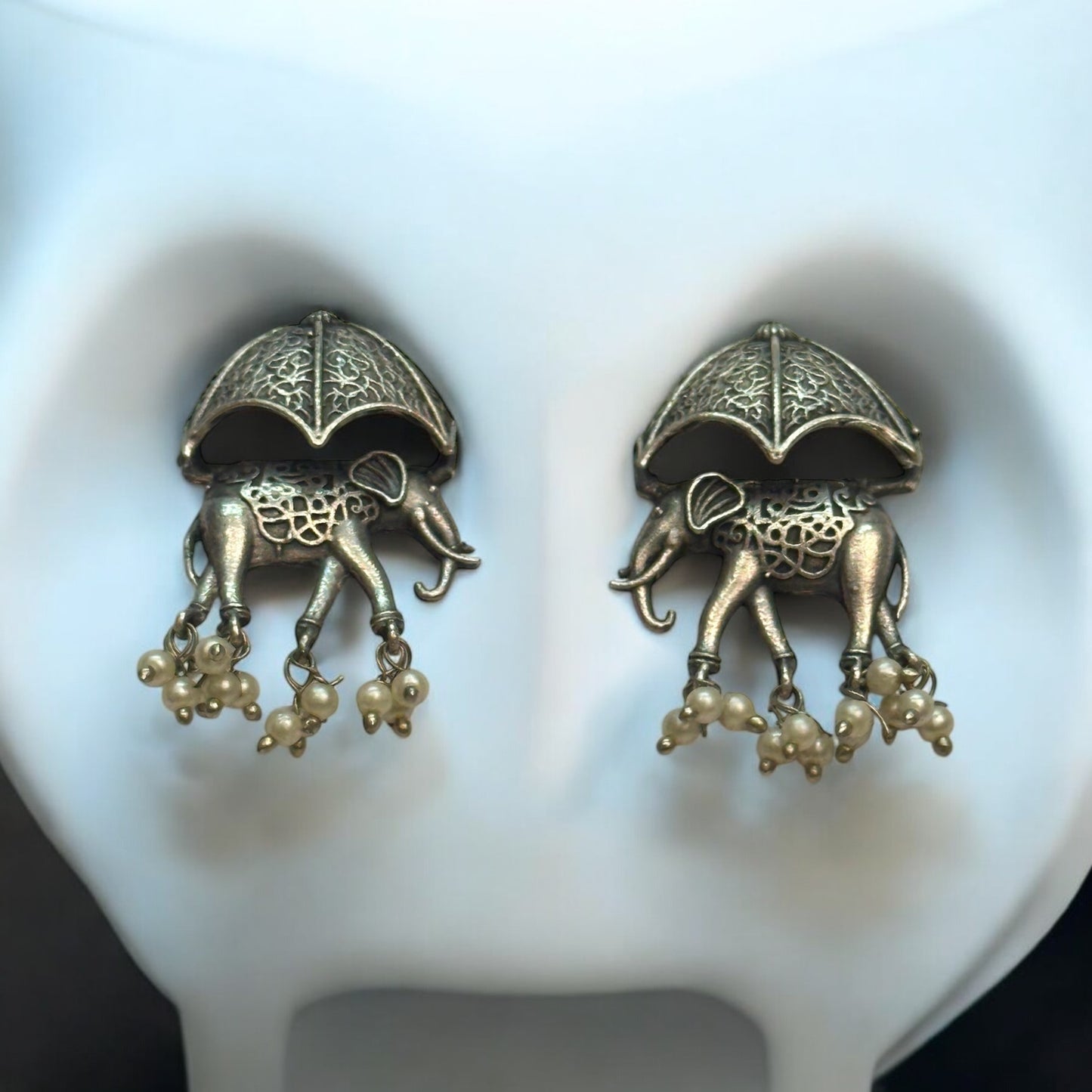 Silver Replica Elephant Design Earrings featuring intricate detailing of elephants under ornate umbrellas with dangling pearl accents, displayed against a white background.