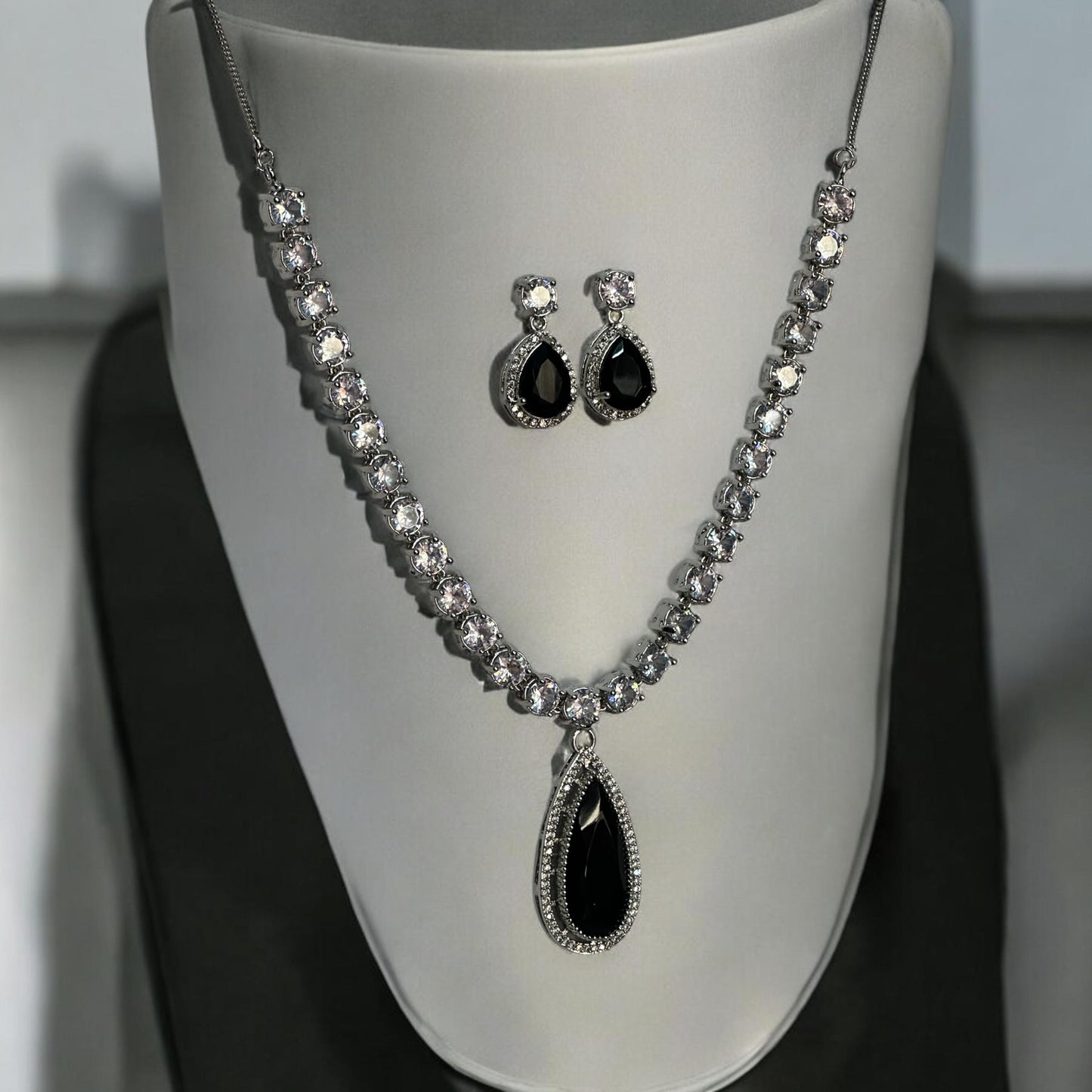 Statement silver black and white diamond necklace set with teardrop pendant and matching earrings displayed on grey bust stand