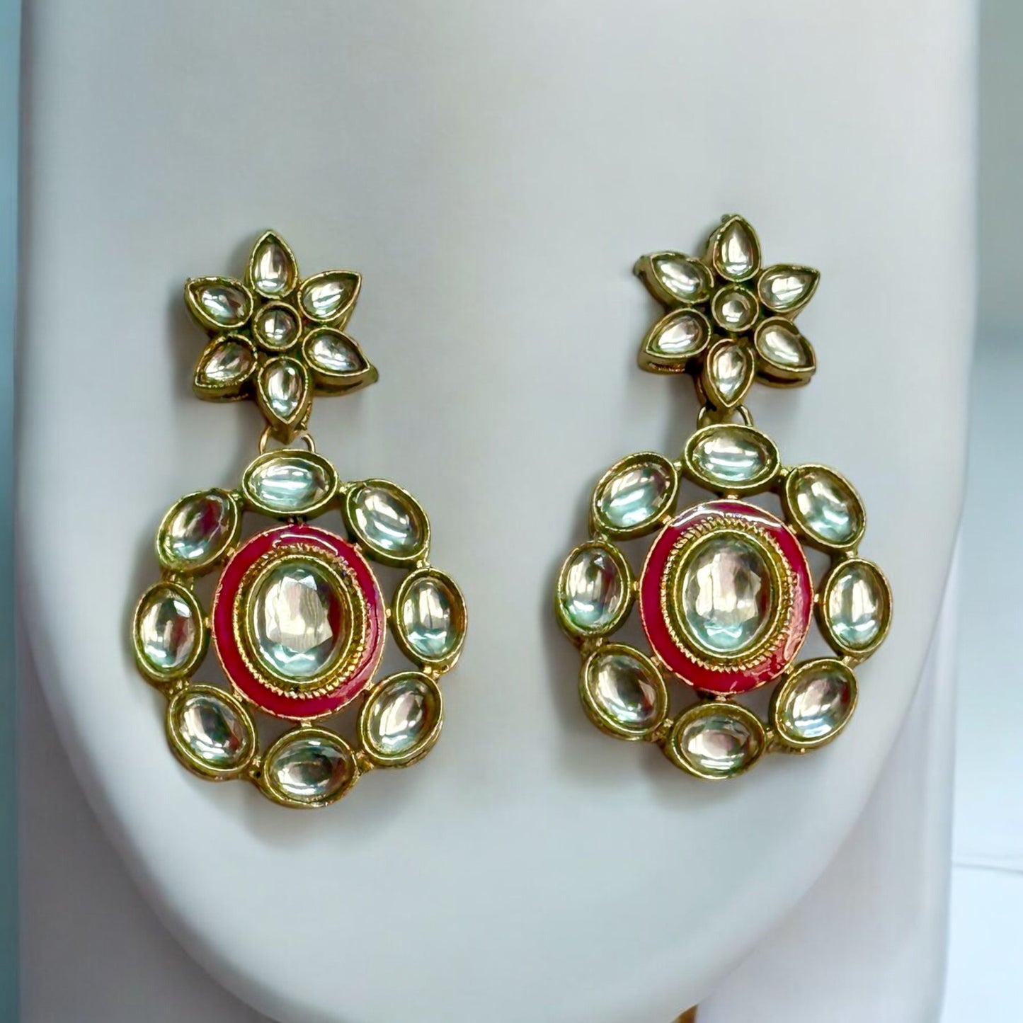 Elegant Kundan necklace sets' earrings featuring intricate floral designs in pink and gold tones, placed on a white coloured jewellery display stand. These are perfect for traditional and festive occasions.