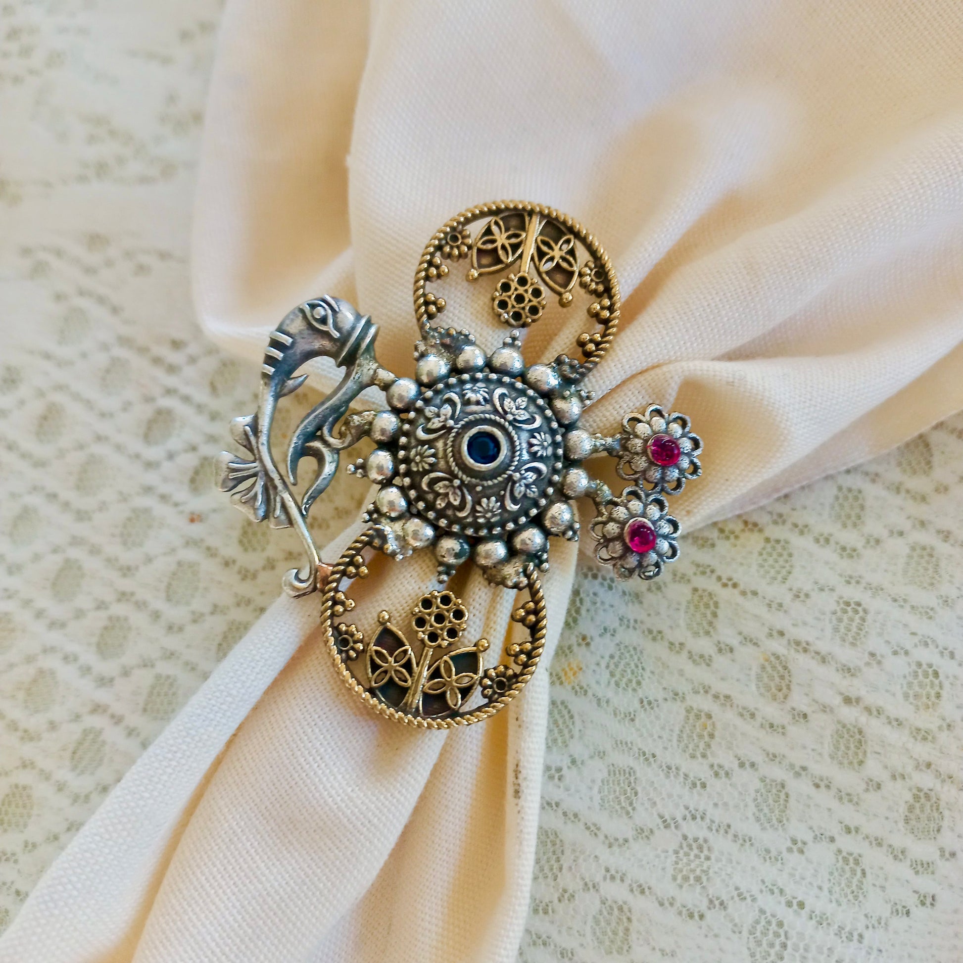 An Adjustable Fusion Oxidised Finger Ring featuring intricate oxidised silver detailing, floral filigree patterns, and delicate gemstone embellishments, over a lace fabric background.