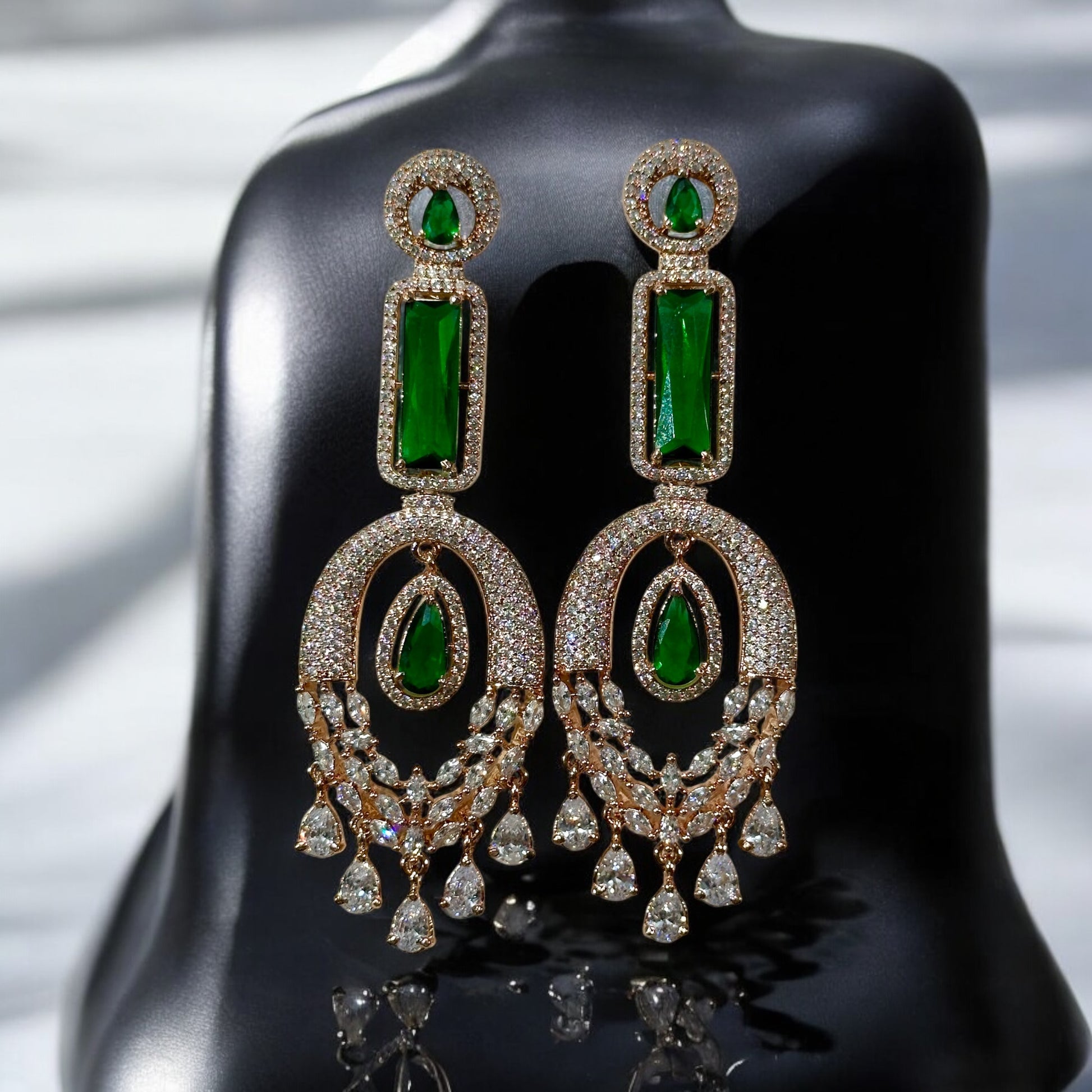 Green American Diamond Statement Earrings on a black colored jewellery display stand with a silver fabric background.