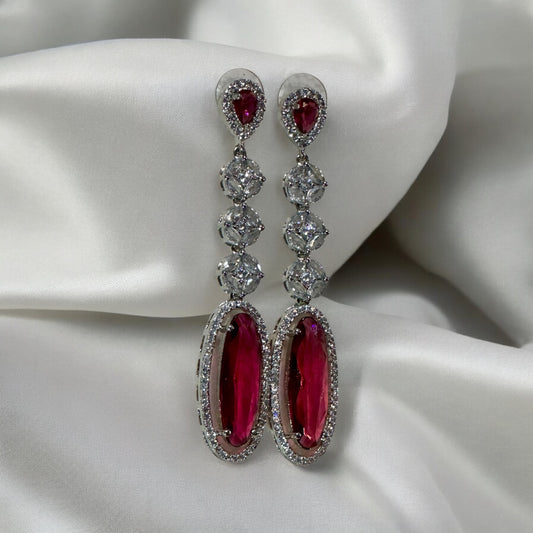 Ruby Colored American Diamond Statement Earrings on a white fabric bakground