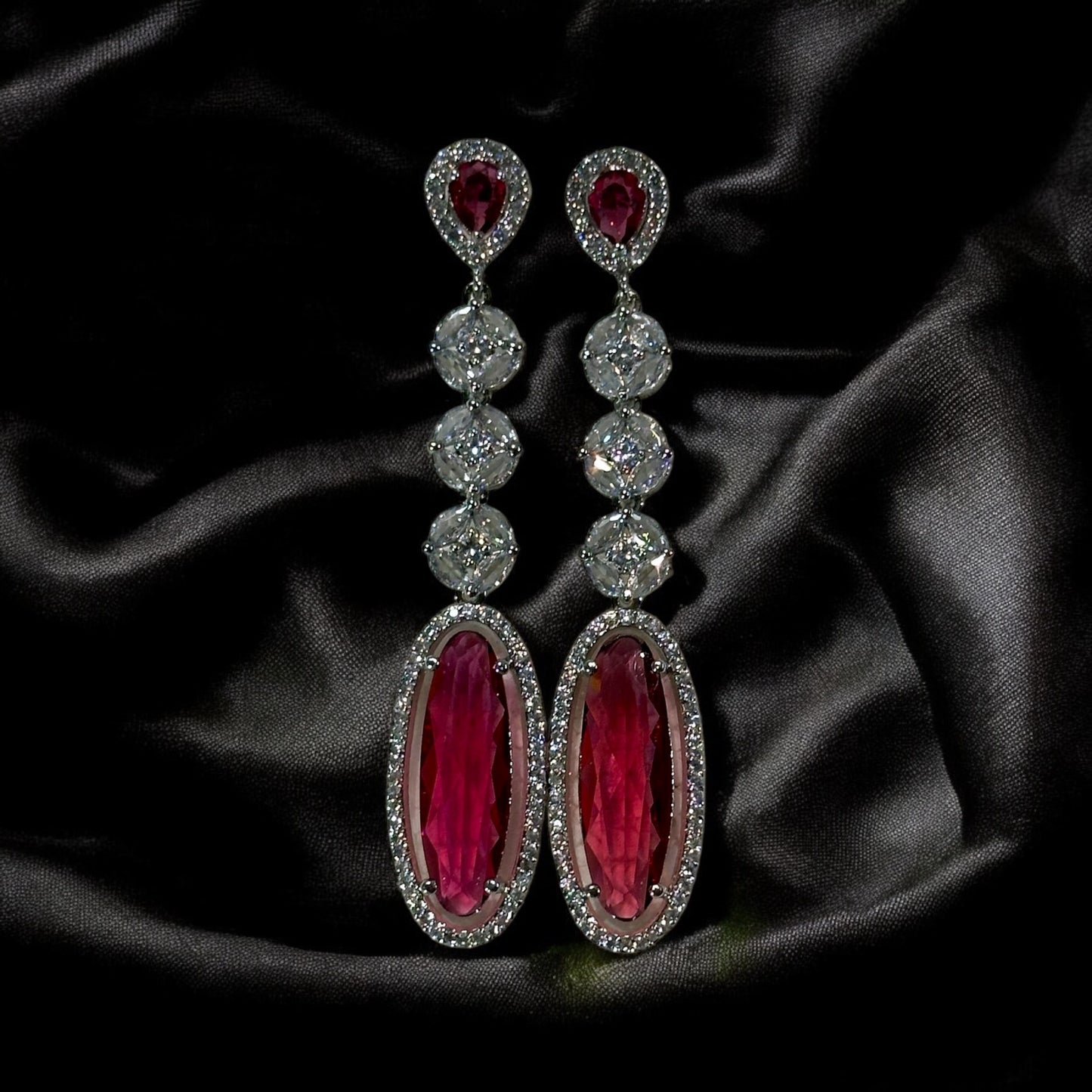 Ruby Colored American Diamond Statement Earrings on a black fabric background