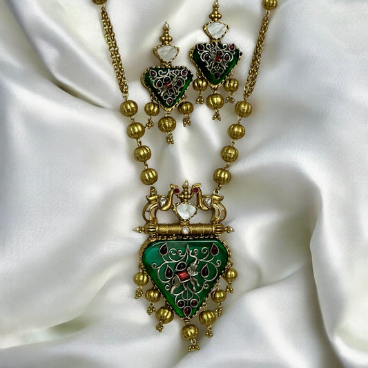 Amrapali-inspired long necklace with green enamel stone pendant and matching earrings on white silk fabric – Bella & Diva
