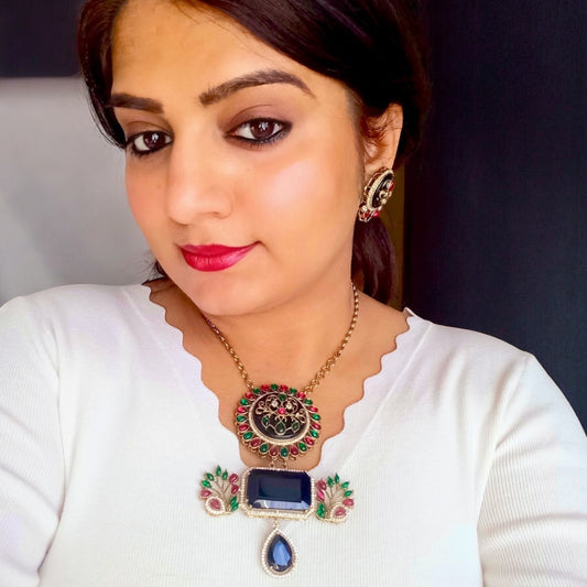 A model in white top displaying an Amrapali-style long necklace with intricate black, red, and green accents, paired with matching earrings in a fusion-inspired design to sell online in UK at bella and diva.