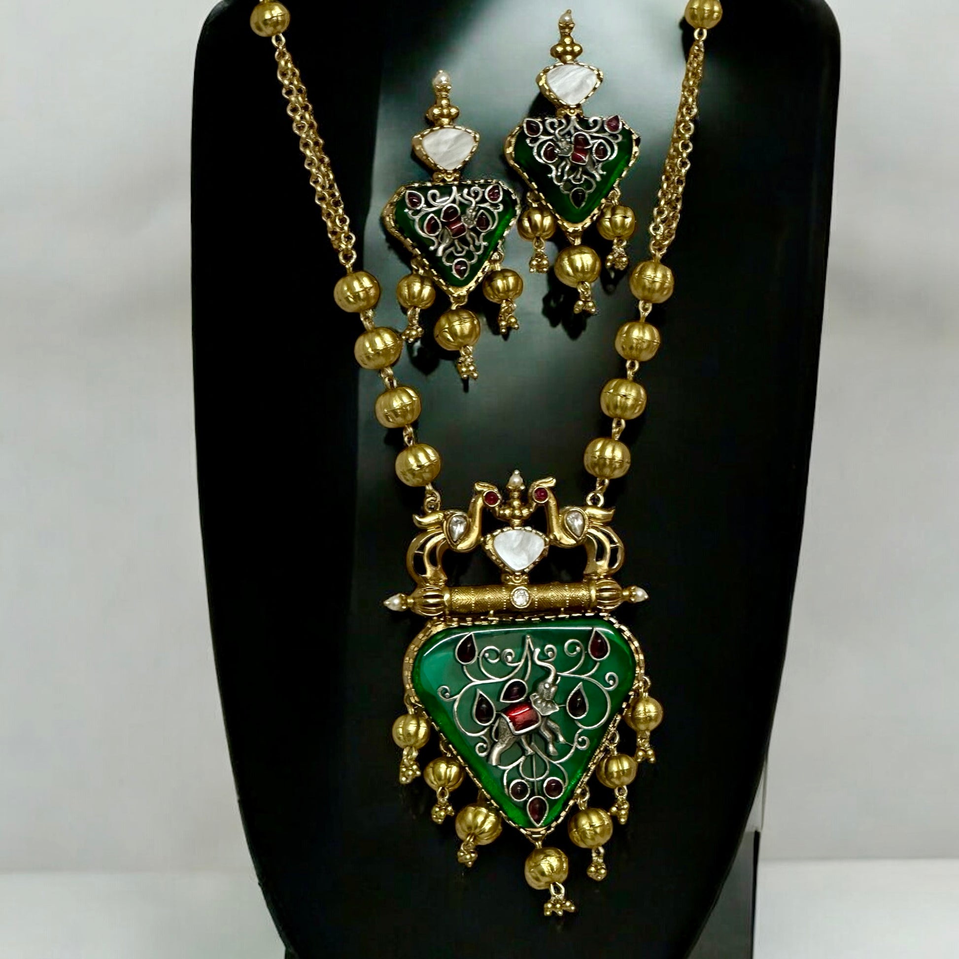 Amrapali-inspired long necklace with green enamel stone pendant and matching earrings on black jewellery display stand – Bella & Diva
