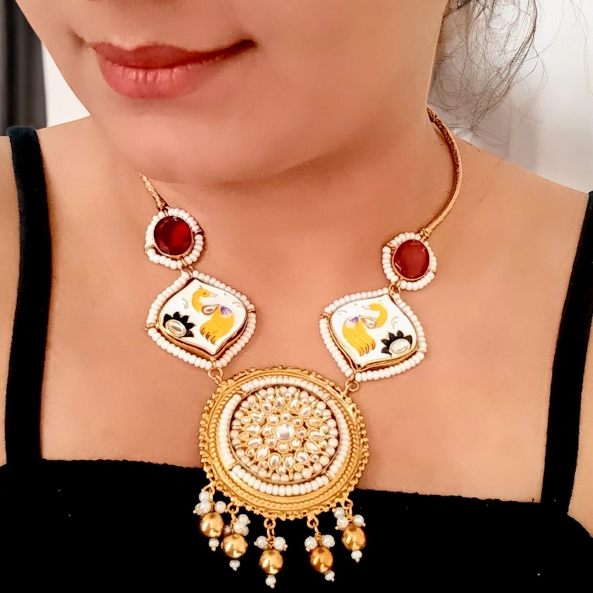 A model displaying an Amrapali Designer Hand-Painted Red Necklace with Studs – a traditional masterpiece with pearl detailing, Kundan stones, and intricate hand-painted motifs.