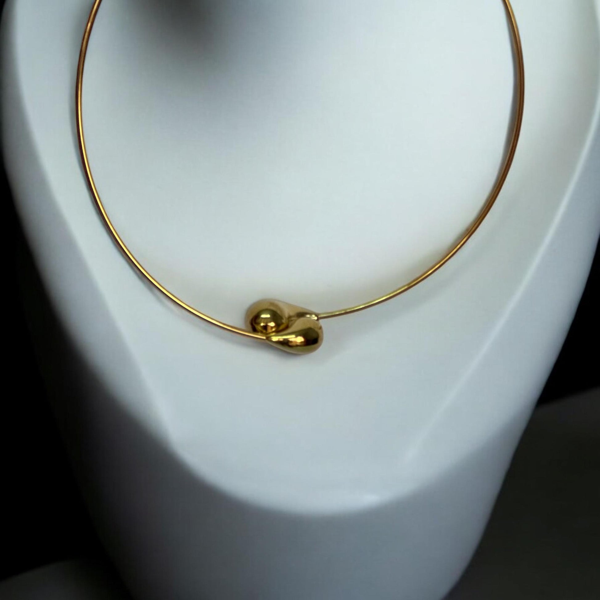 Anti-Tarnish Hasli Design Partywear Gold-Toned Necklace with Minimalistic Style placed on a white coloured jewellery display stand.