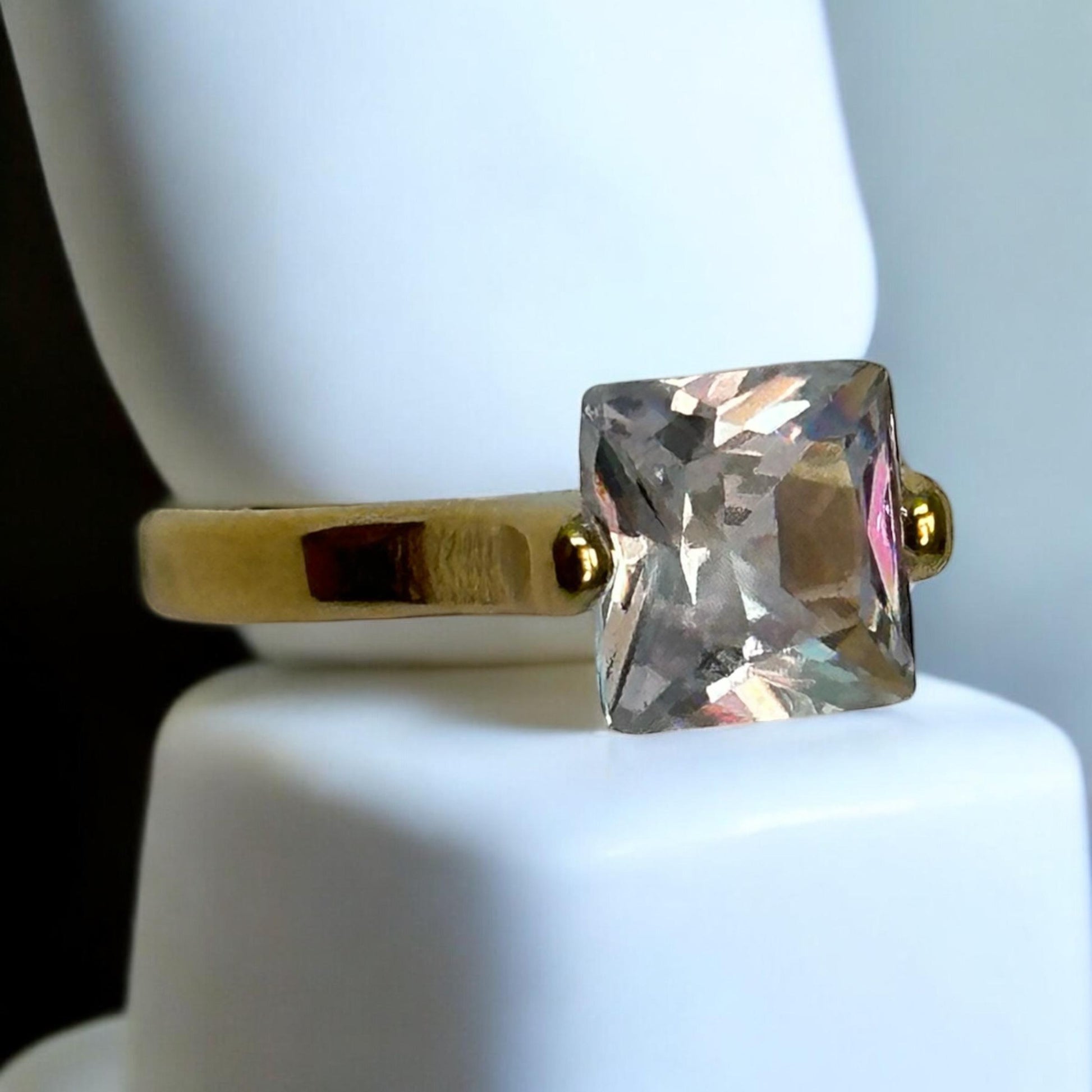 Anti-Tarnish Single Diamond Finger Ring in gold-tone finish, featuring a sparkling square-cut stone, displayed on a white stand with its modern and minimalistic design.