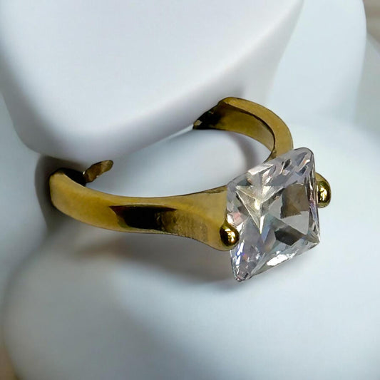 Anti-Tarnish Single Diamond Finger Ring in gold-tone finish, featuring a sparkling square-cut stone, displayed on a white stand with its modern and minimalistic design.