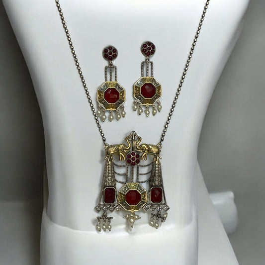 Dual Tone Silver Replica Necklace Set in Ruby red and golden color featuring a detailed pendant with ruby red stones and hanging pearls, displayed on a white mannequin with a soft black and white gradient background.