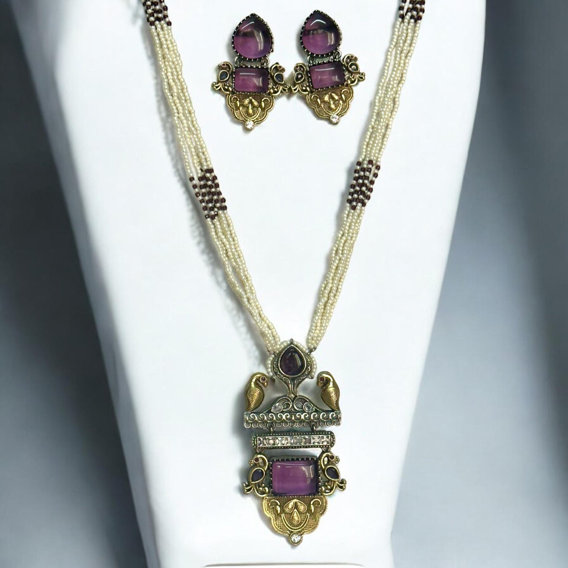 Dual Tone Silver Replica Purple Necklace Set with a multi-strand white pearl mala, featuring a bird motif pendant with purple stones, displayed on a white mannequin.