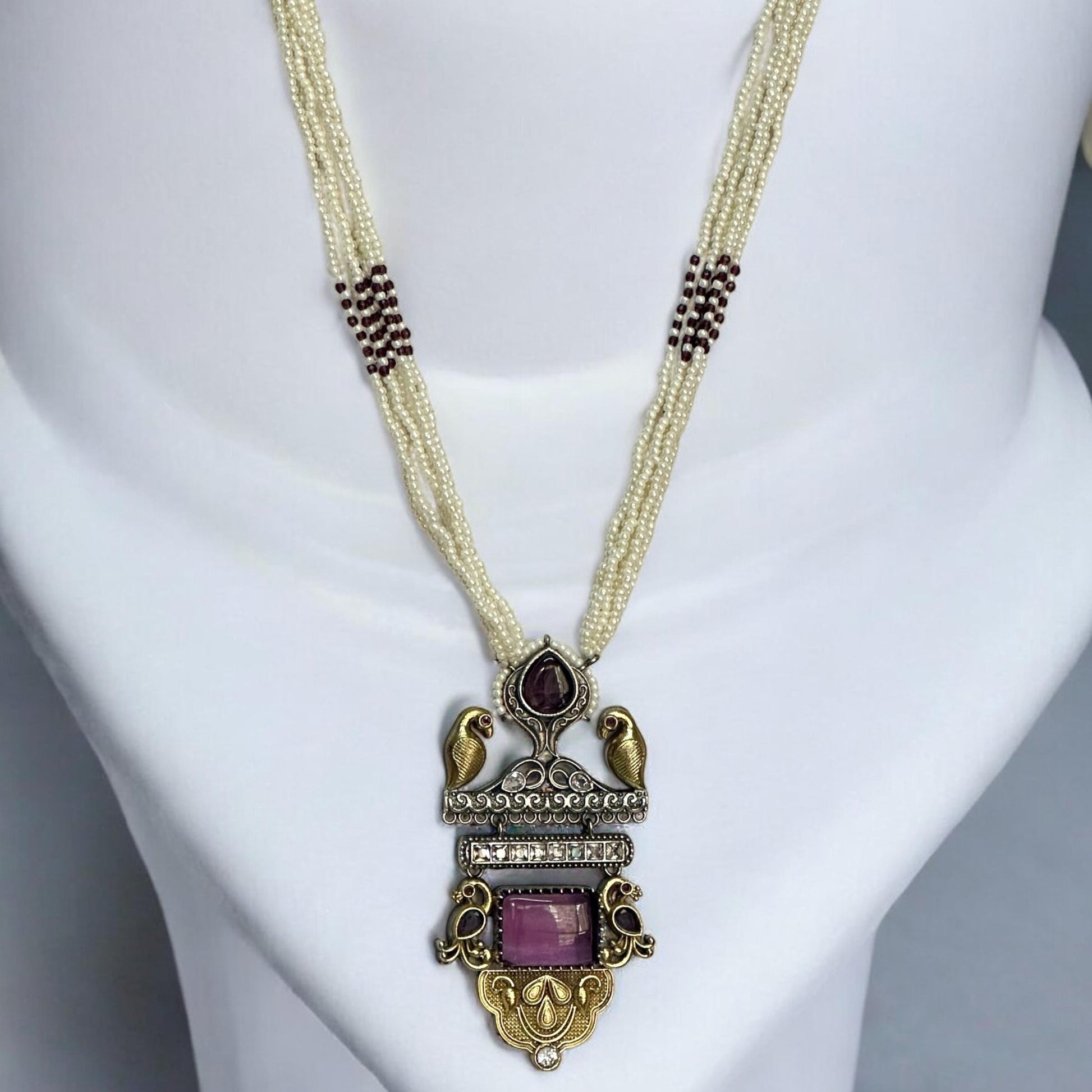  Dual Tone Silver Replica Purple Necklace Set with a multi-strand white pearl mala, featuring a bird motif pendant with purple stones, displayed on a white mannequin.