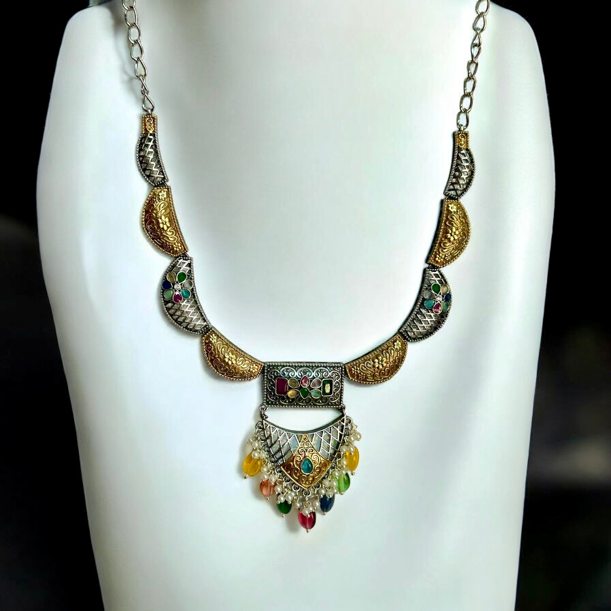 Dual tone silver look alike necklace with multicolour beads placed on a white coloured jewellery display stand.