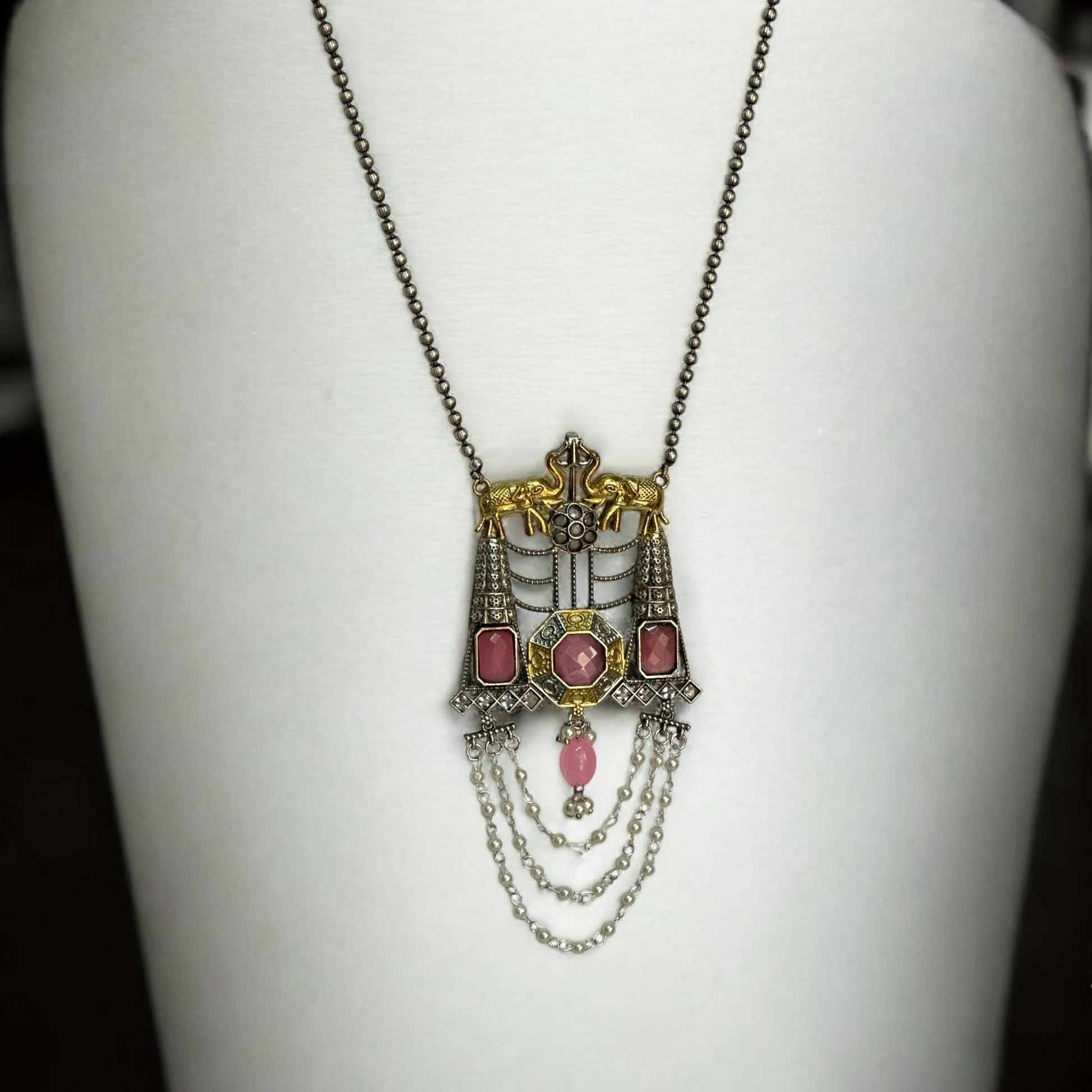 Dual-tone Silver Replica Long Pendant Necklace with Pink Monalisa Stone Accents and Intricate Chain Detailing PLACED ON A WHITE COLOURED JEWELLERY DISPLAY STAND. 