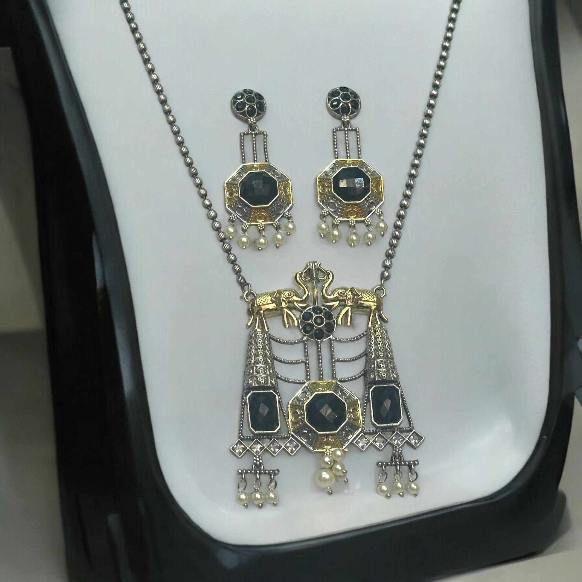 Dual Tone Silver Replica Necklace Set in green and golden color featuring a detailed pendant with green stones and hanging pearls, displayed on a white mannequin with a soft black and white gradient background.