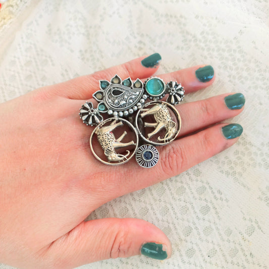 An Elephant Design Oxidised Fusion Finger Ring, featuring intricate oxidised silver detailing, a regal elephant motif, and gemstone embellishments, worn on a hand with green-painted nails over a lace fabric background.