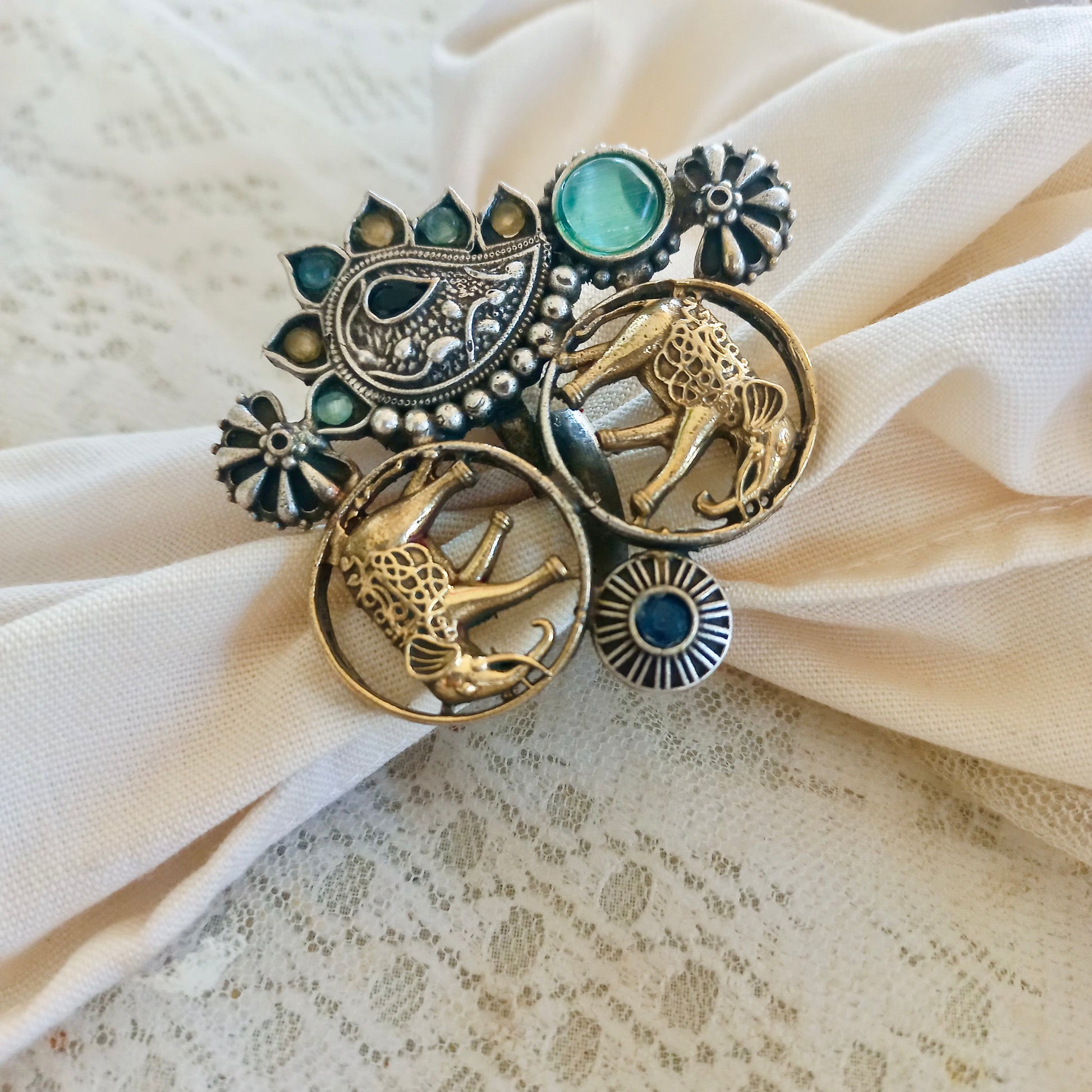 An Elephant Design Oxidised Fusion Finger Ring, featuring intricate oxidised silver detailing, a regal elephant motif, and gemstone embellishments, over a lace fabric background.