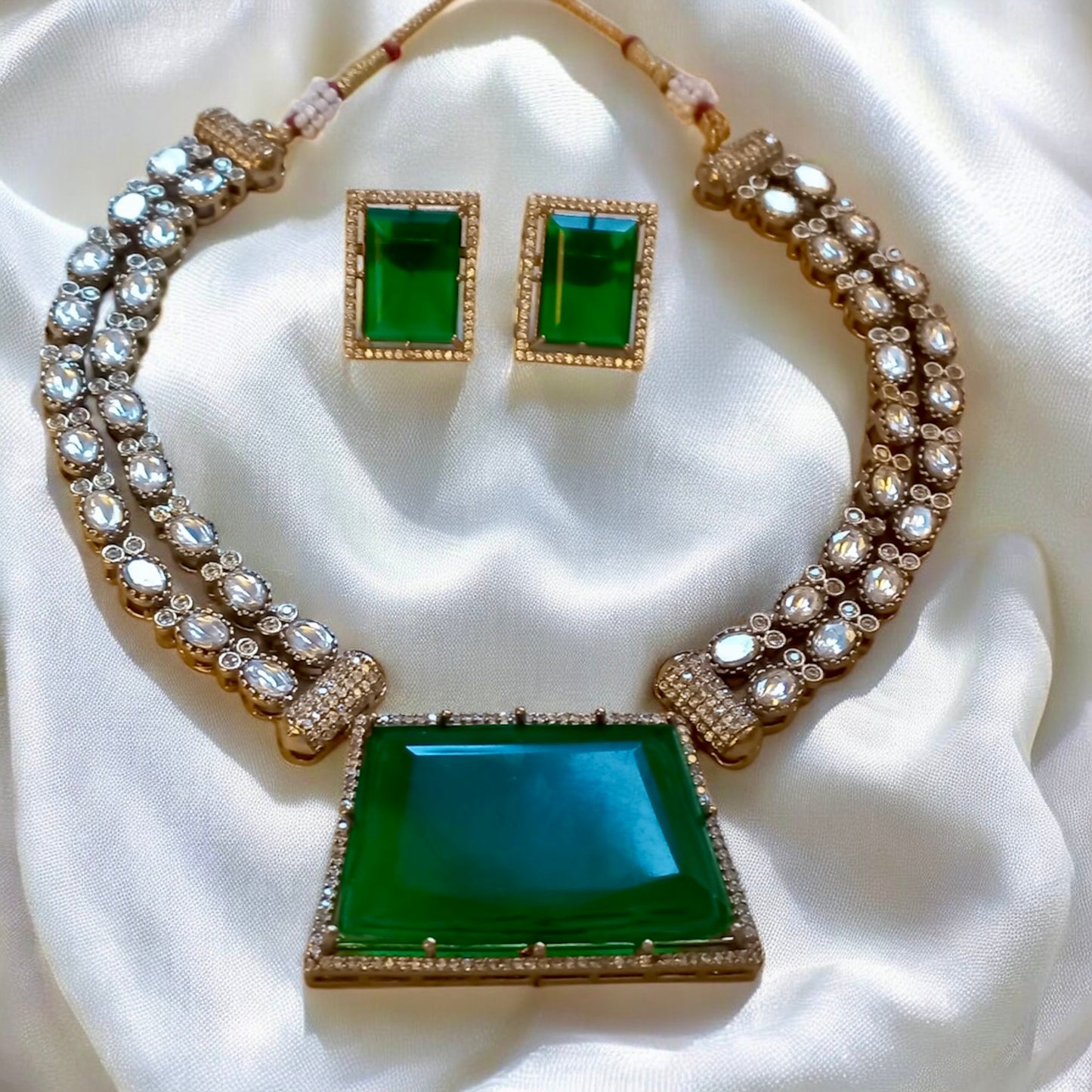 Emerald green moissanite double layer necklace set with crystal-studded pendant and matching rectangular earrings on White Fabric  background