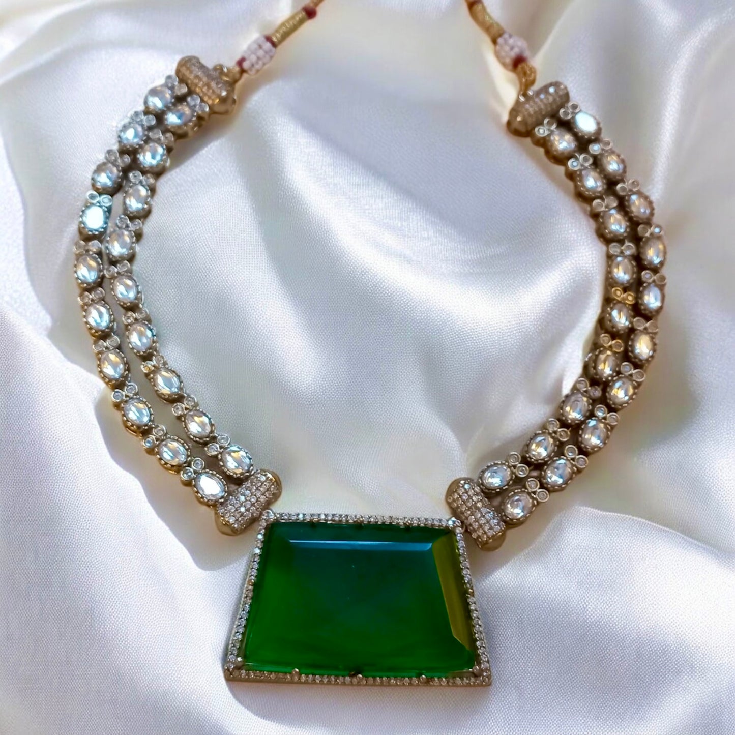 Emerald green moissanite double layer necklace set with crystal-studded pendant on White Fabric  background