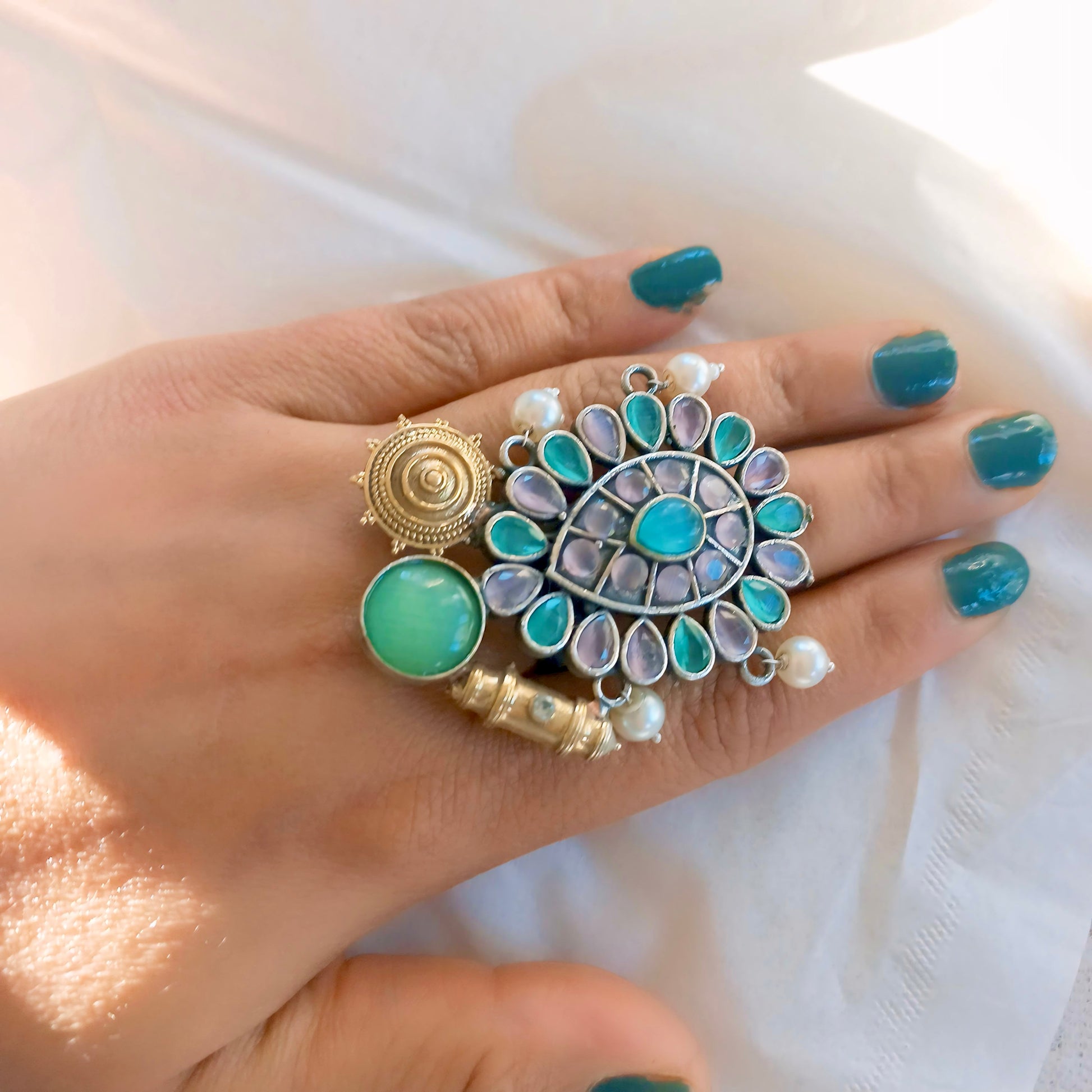 Fusion ring with multicolor gemstones on a hand model.