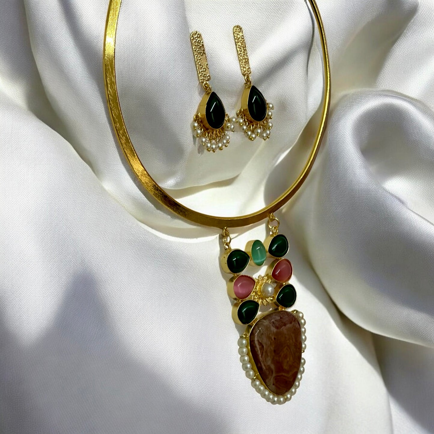 Side view of Golden fusion hasli necklace with multicolour Monalisa stone pendant and matching earrings on white fabric – Bella & Diva