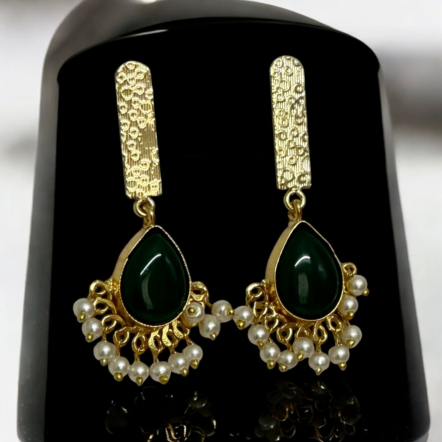 Golden fusion hasli necklace set's earrings with dark green Monalisa stone and hanging white pearls on a black coloured jewellery display stand – Bella & Diva