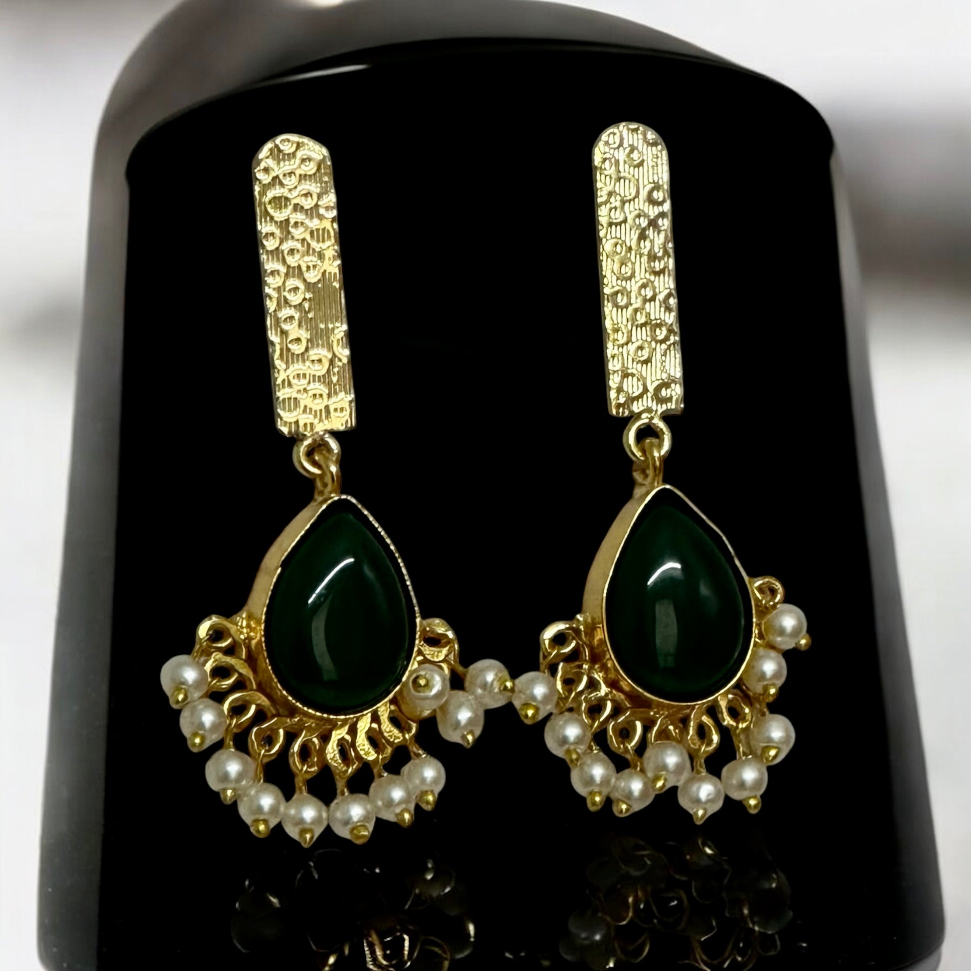 Golden fusion hasli necklace set's earrings with dark green Monalisa stone and hanging white pearls on a black coloured jewellery display stand – Bella & Diva