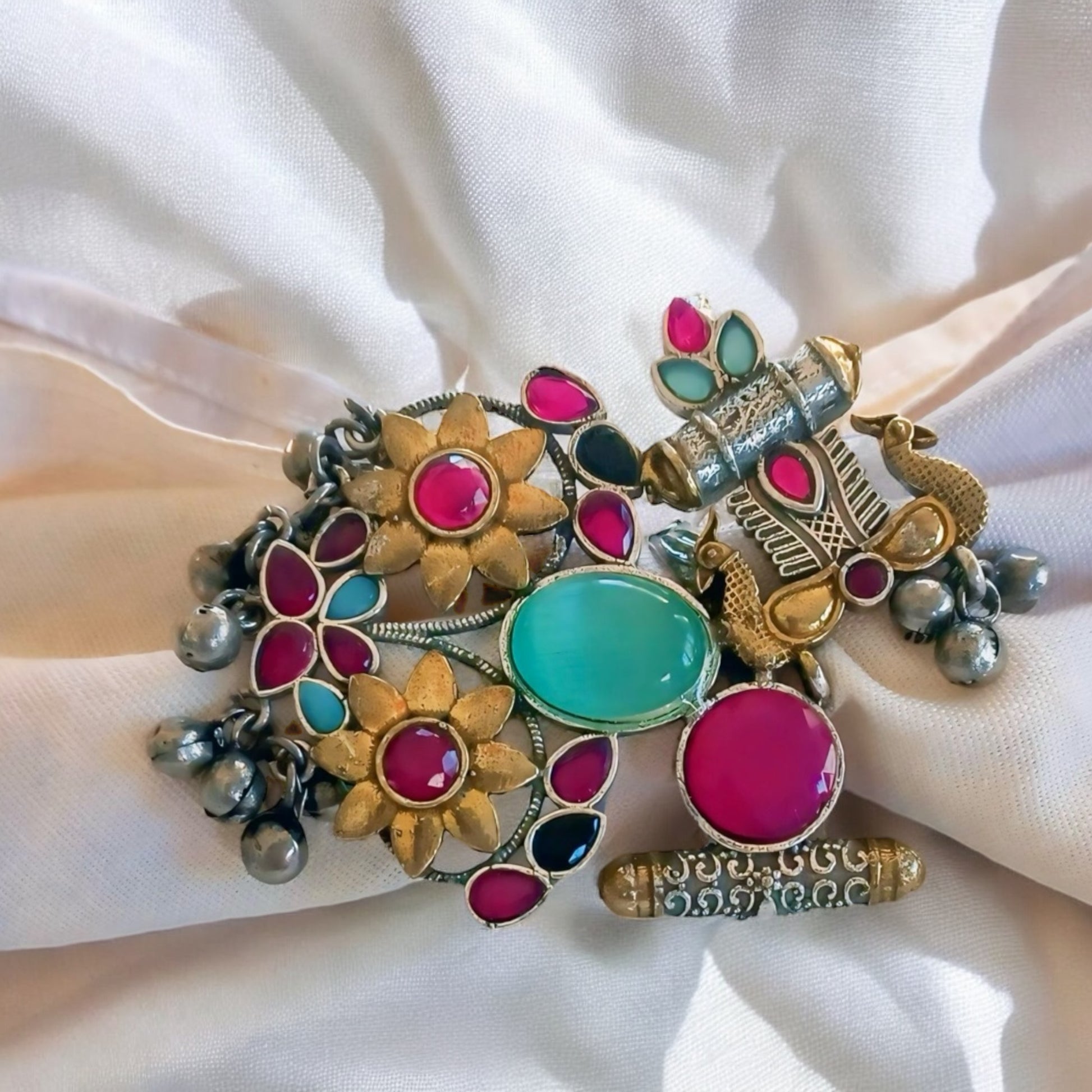 A white fabric wearing a vibrant Fusion Silver Multi Color Adjustable Ring with antique silver finish and colourful stones, styled on a satin fabric background.