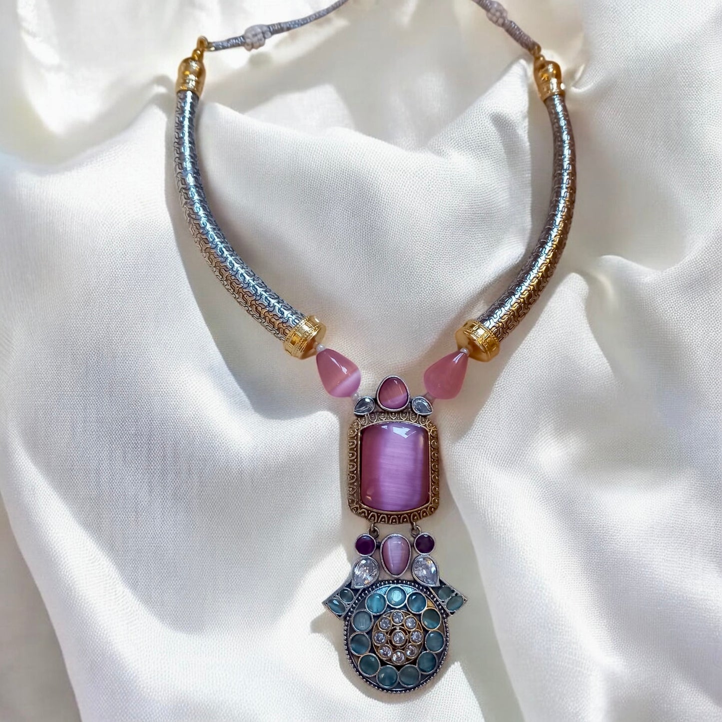 German silver hasli-style necklace with pink Monalisa stones and antique detailing on satin background