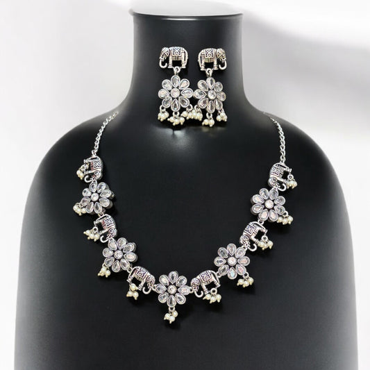 German silver necklace set in elephant and floral design with white bead drops and matching oxidised earrings displayed on black mannequin