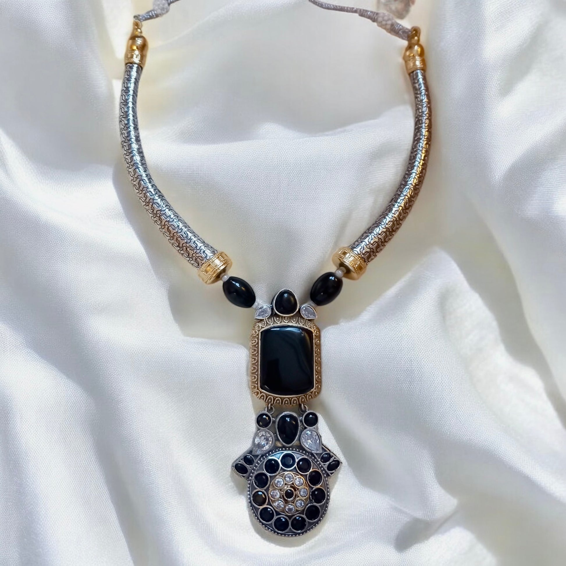 German silver hasli necklace with black Monalisa stones and antique oxidised pendant on cream satin background