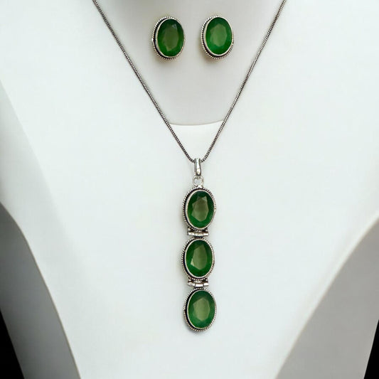 German Silver Long Chain Pendant Set featuring three vertically aligned green oval gemstones in a silver frame, paired with matching green stud earrings, displayed on a white mannequin background.