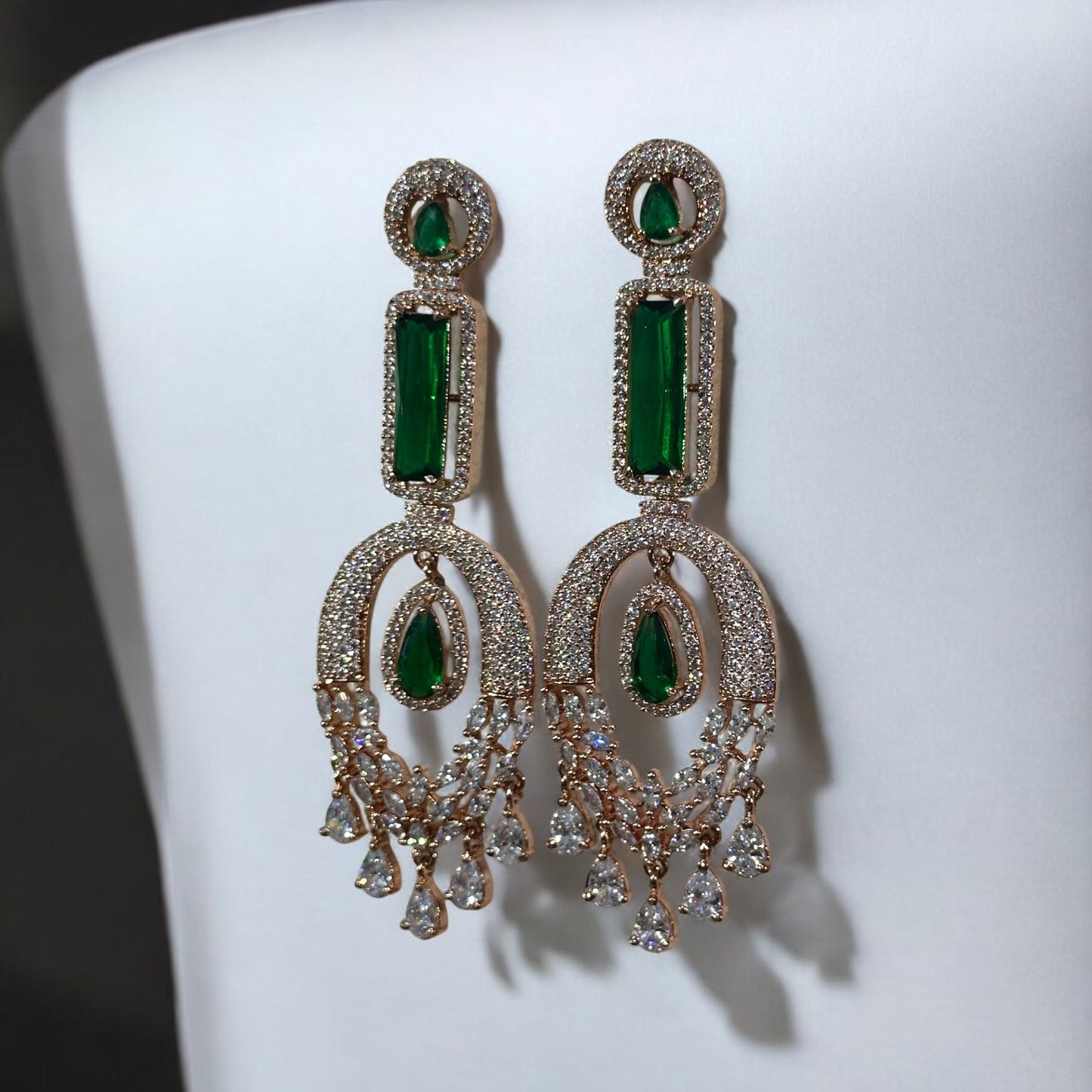 Green American Diamond Statement Earrings on a black colored jewellery display stand with a pure white fabric background.